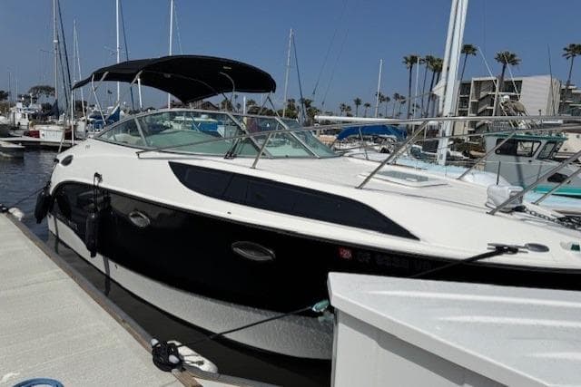 2010 Bayliner 255 Cruiser docked at a marina under clear blue skies.