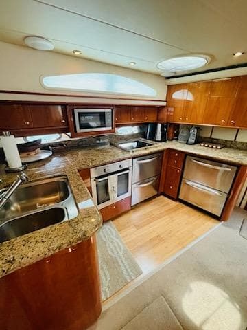 Luxurious kitchen in 2006 Neptunus 55 Cabrio yacht with modern appliances and wood cabinetry.