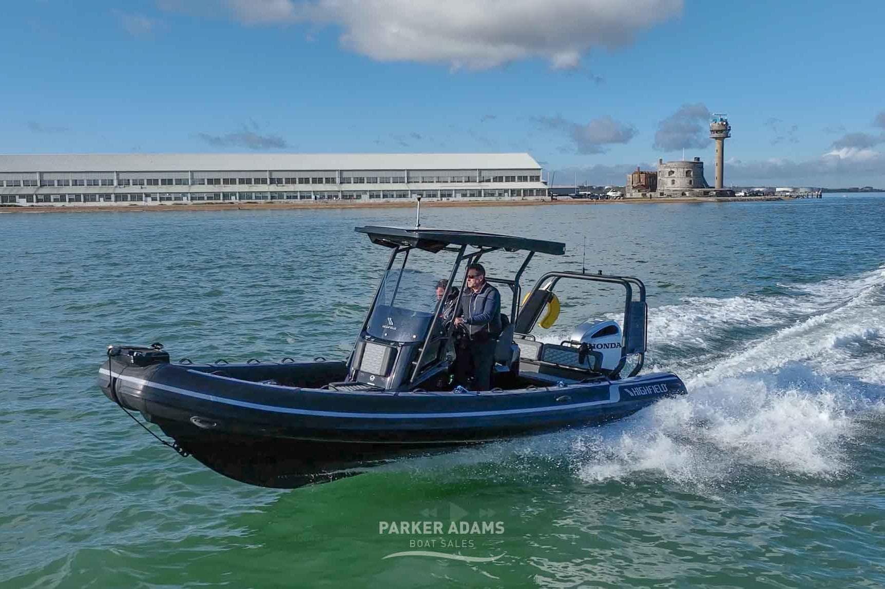 2025 Highfield Sport 700 boat cruising on water near coastal buildings and lighthouse.