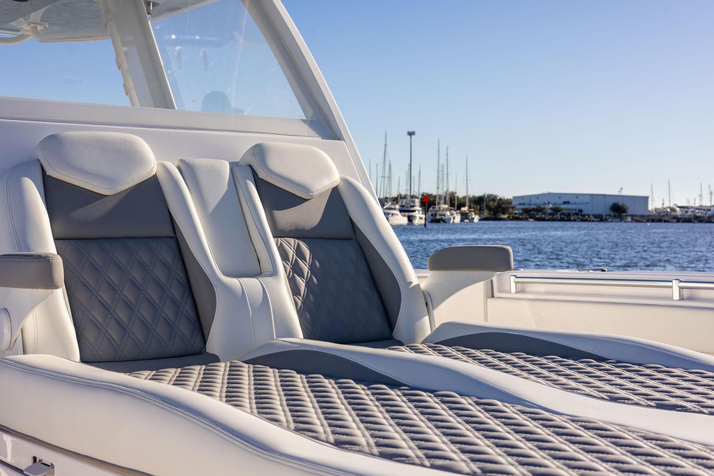Luxurious seating on 2026 Invincible 38 Catamaran, with marina view in the background.