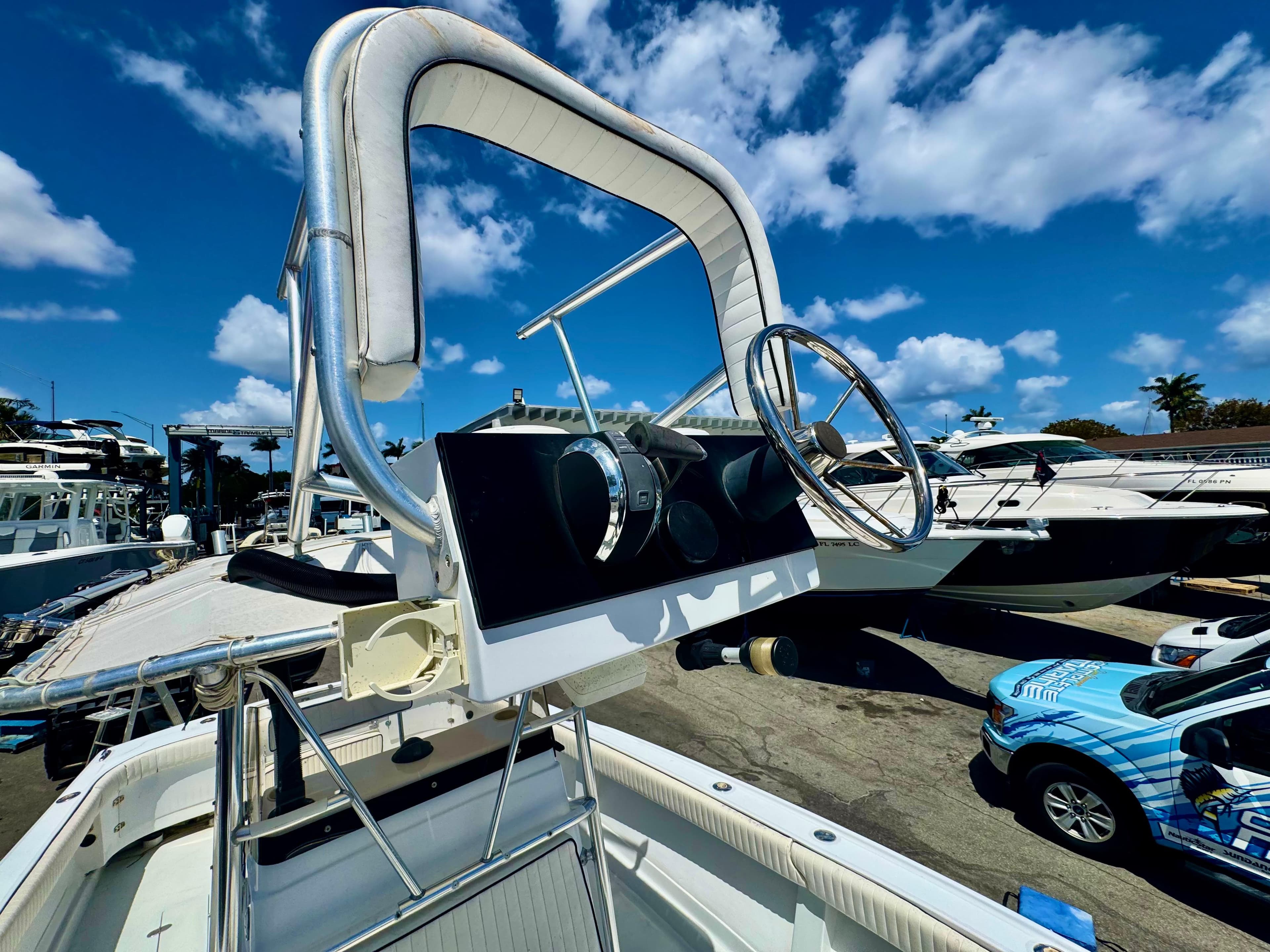 1963 Bertram 25 Mark II convertible sport cruiser helm with steering wheel, docked under blue sky.