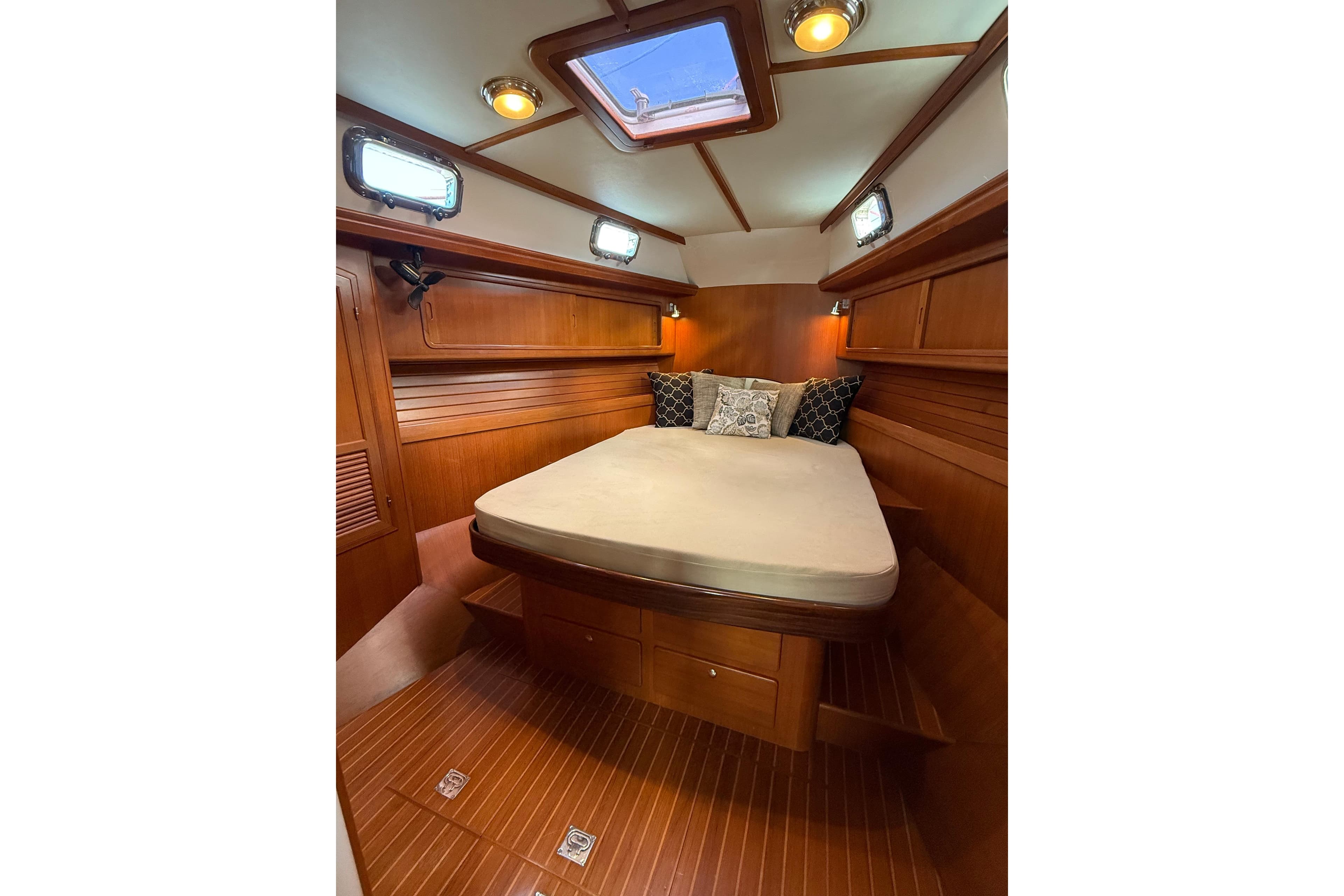 Luxurious cabin interior of 2012 Outbound 46 yacht with wooden finish and cozy bedding.