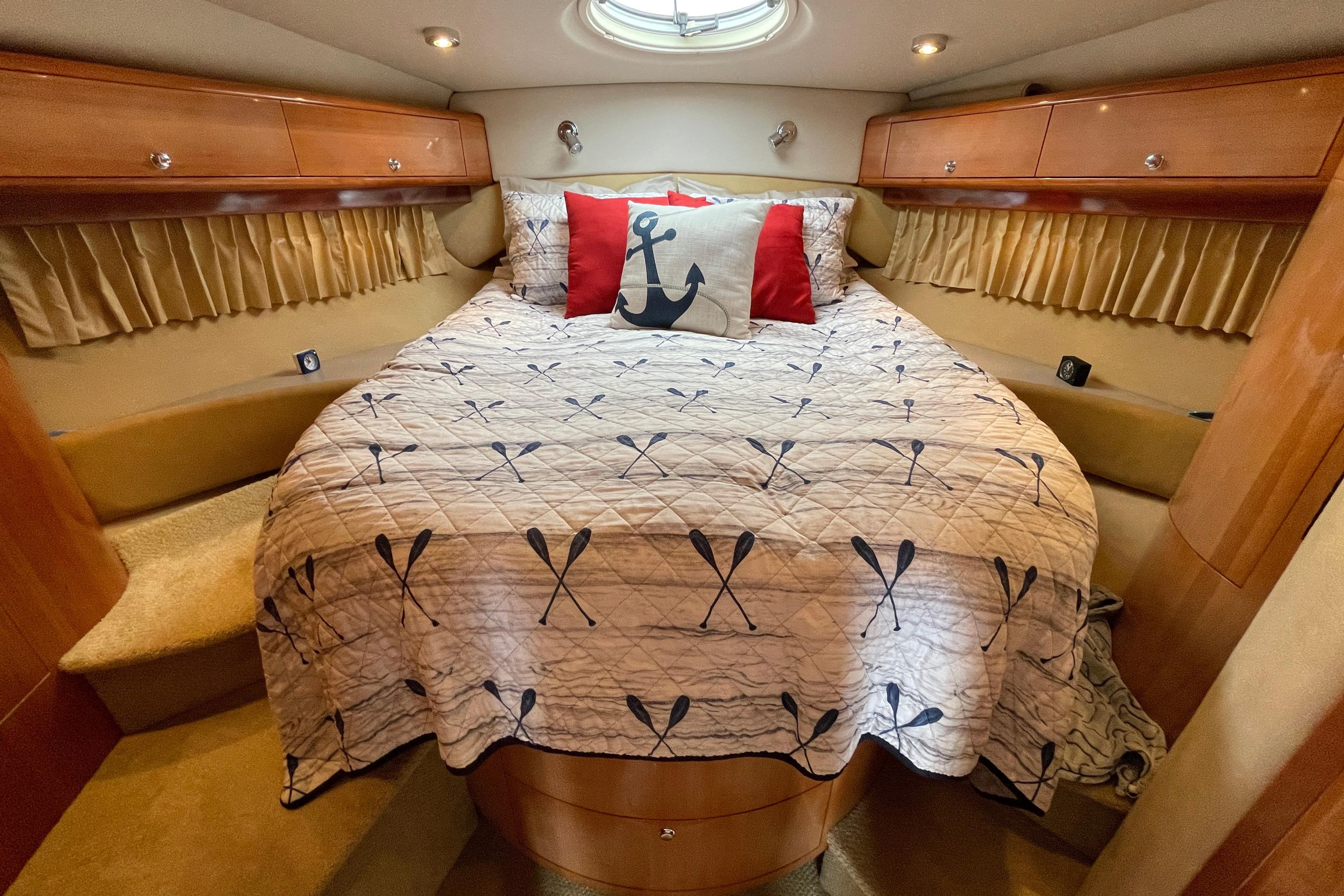 Luxurious 2004 Regal Commodore 4260 yacht cabin with nautical-themed bedding and elegant wood finishes.