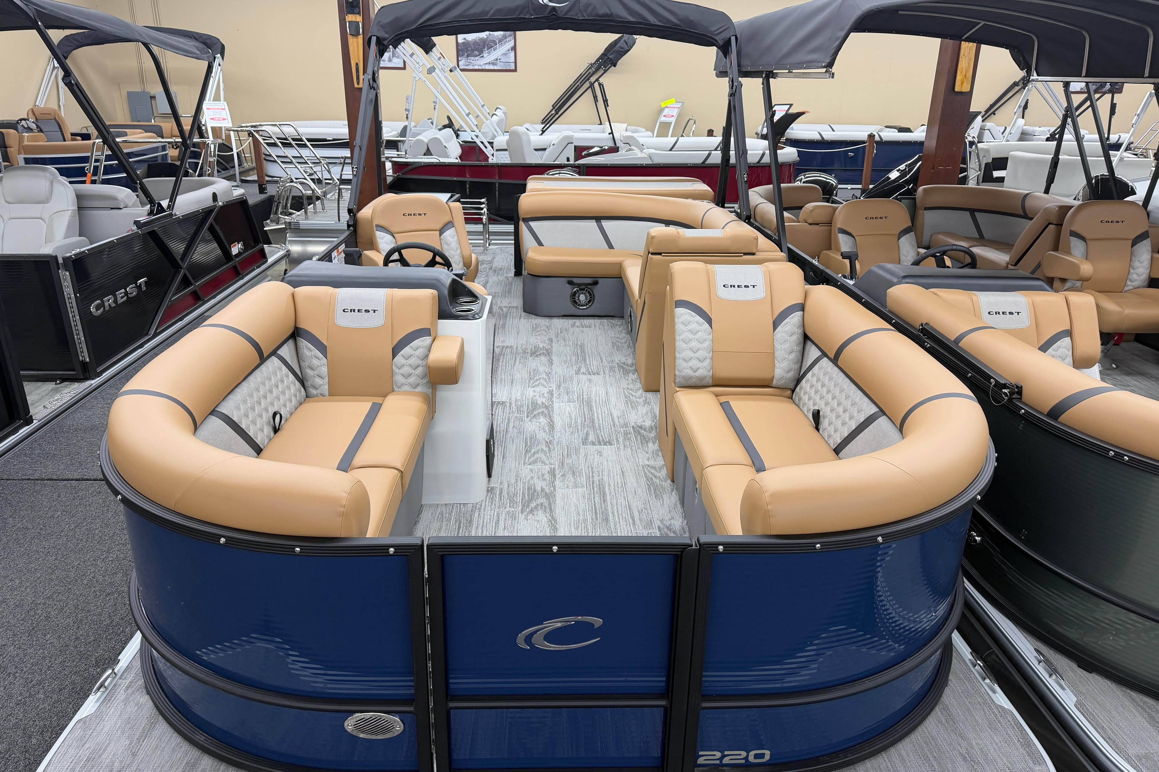 2025 Crest Classic 220 pontoon boat with tan seating and blue exterior in showroom.