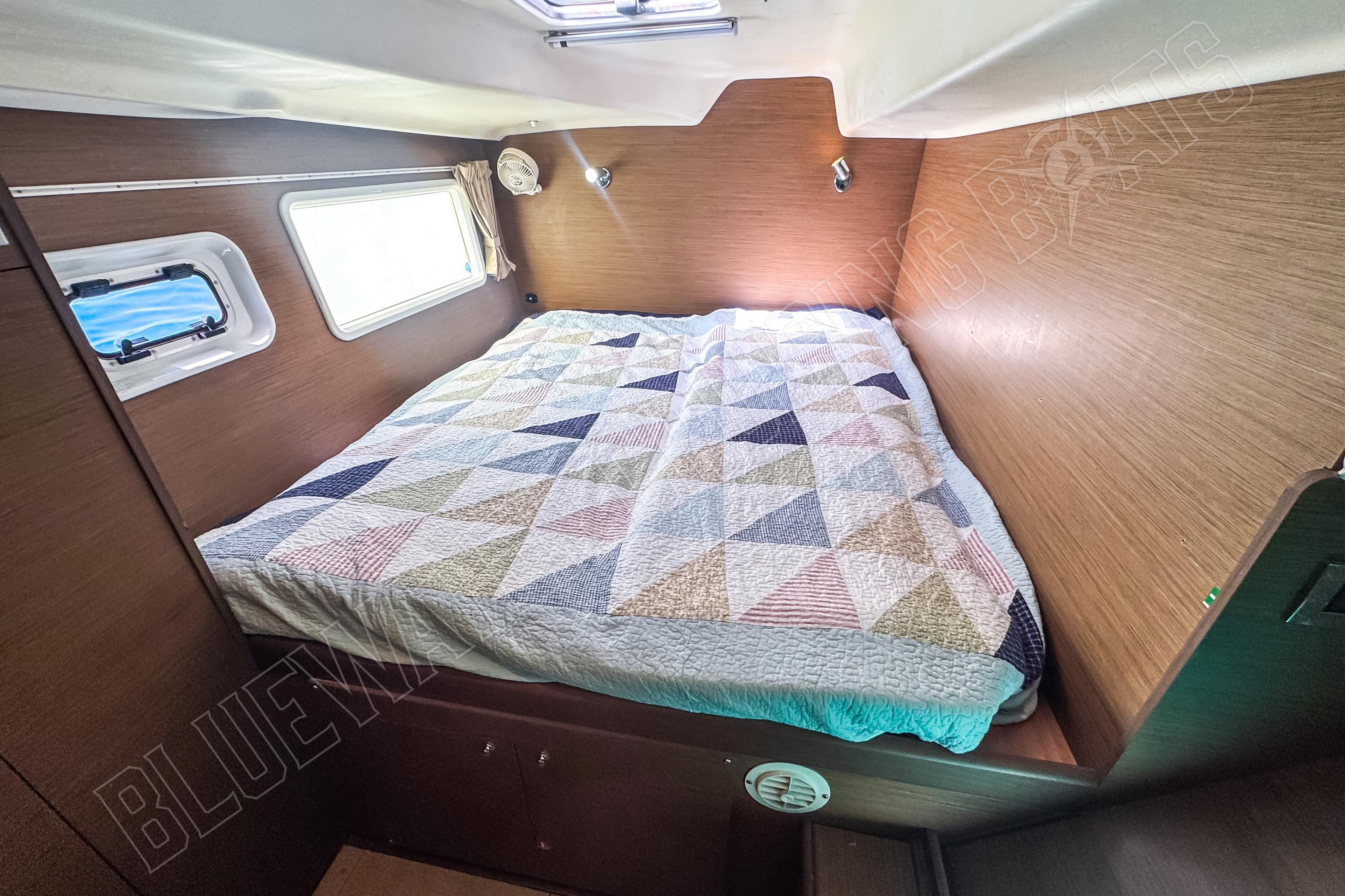 Cozy cabin interior of 2019 Lagoon 380 S2 with geometric-patterned bedspread.