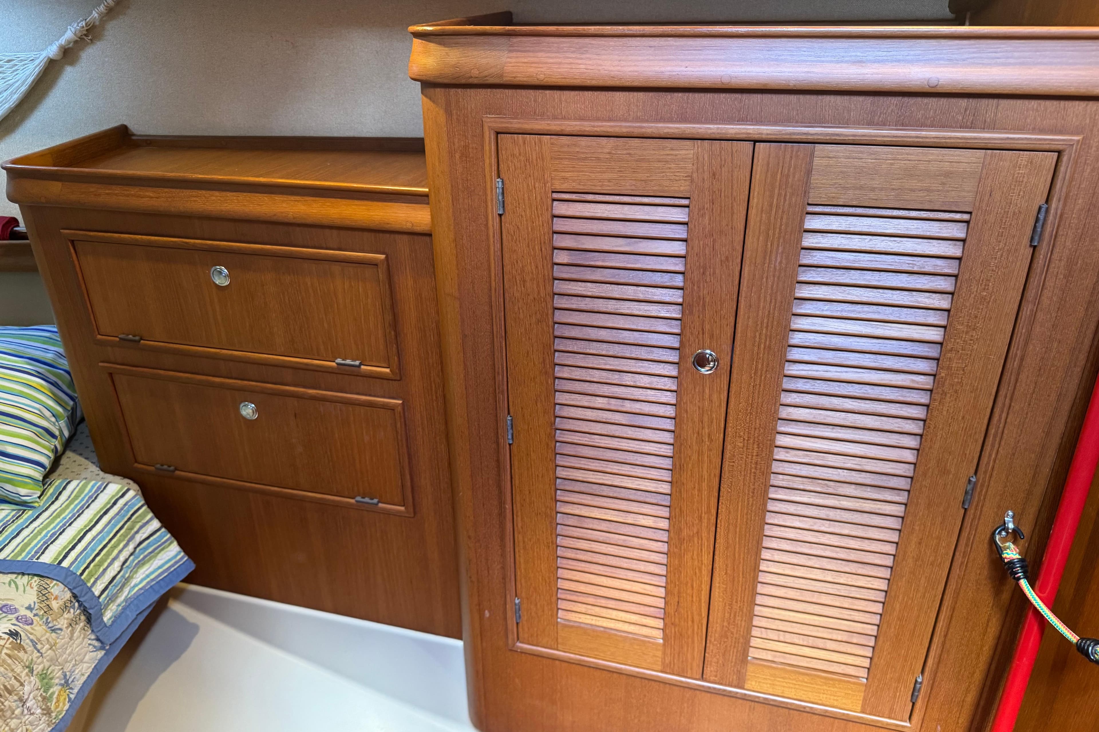 Wooden cabinetry inside a 2004 Island Packet 420 sailboat, featuring drawers and a louvered door.