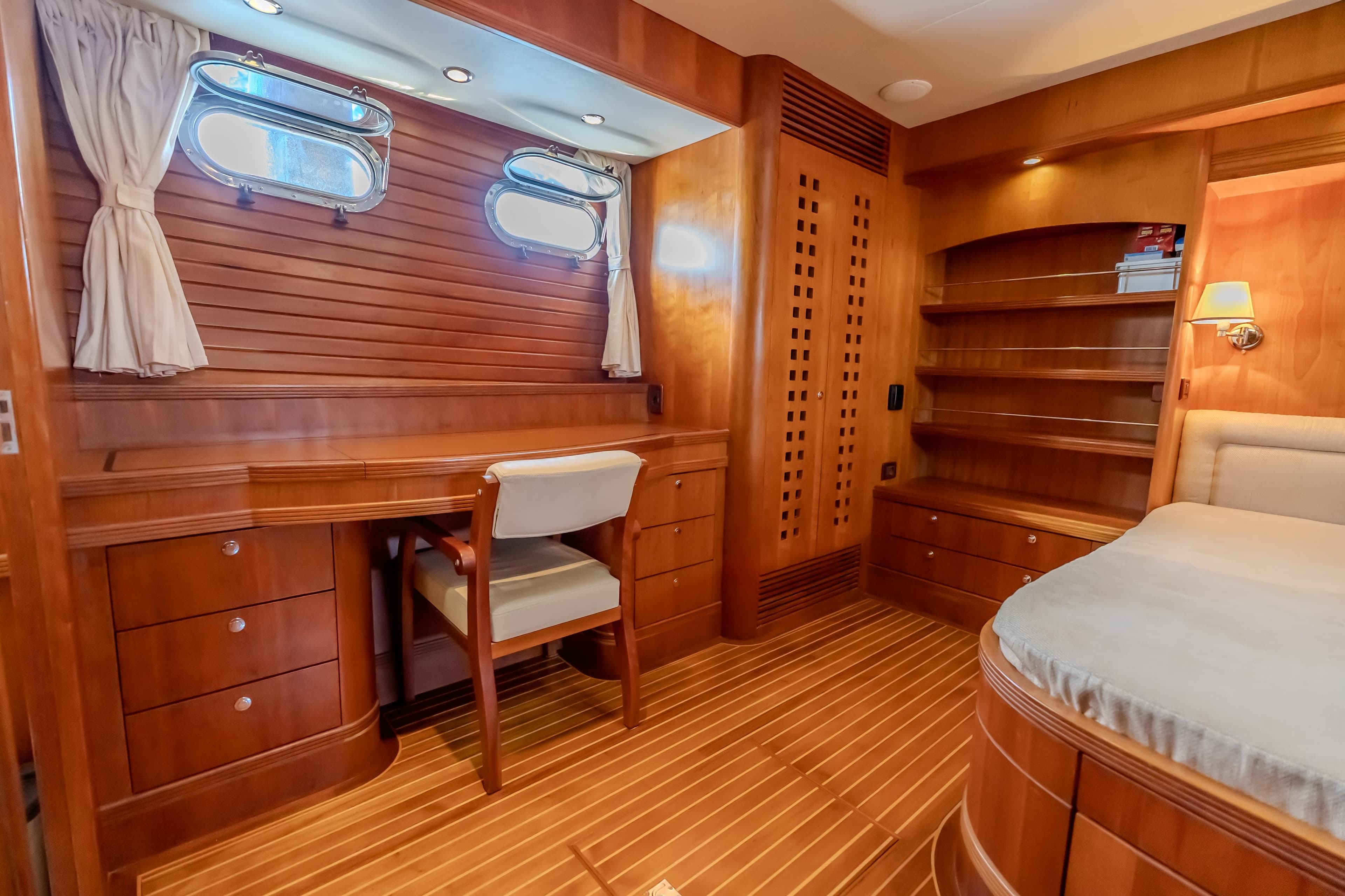 Luxurious wooden interior of a 2004 Selene 62 yacht cabin with desk and shelves.