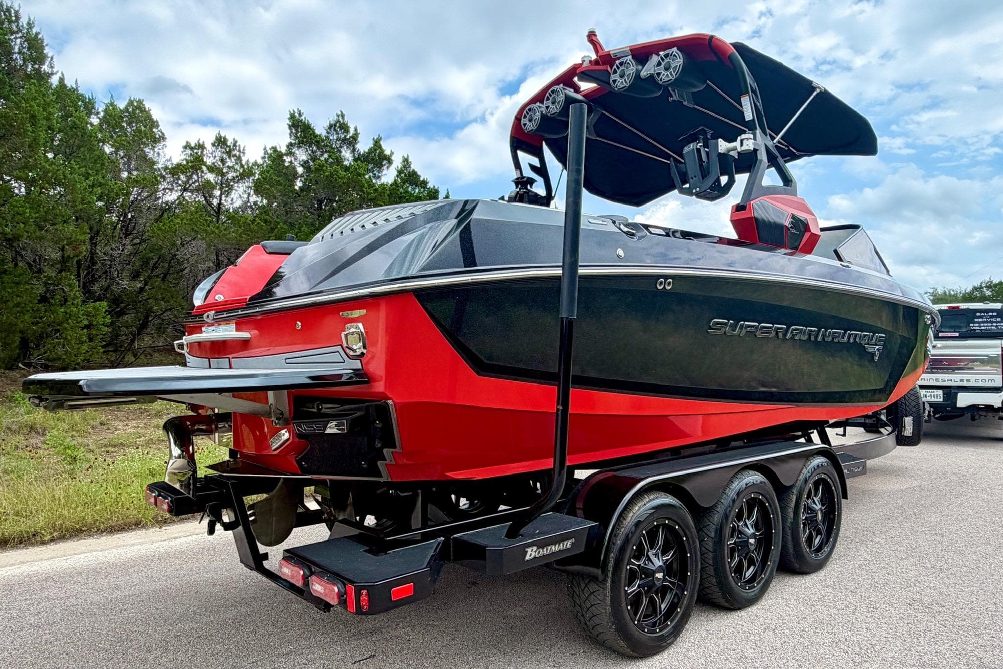 2019 Nautique Super Air Nautique G25 boat on trailer, red and black design, parked outdoors.