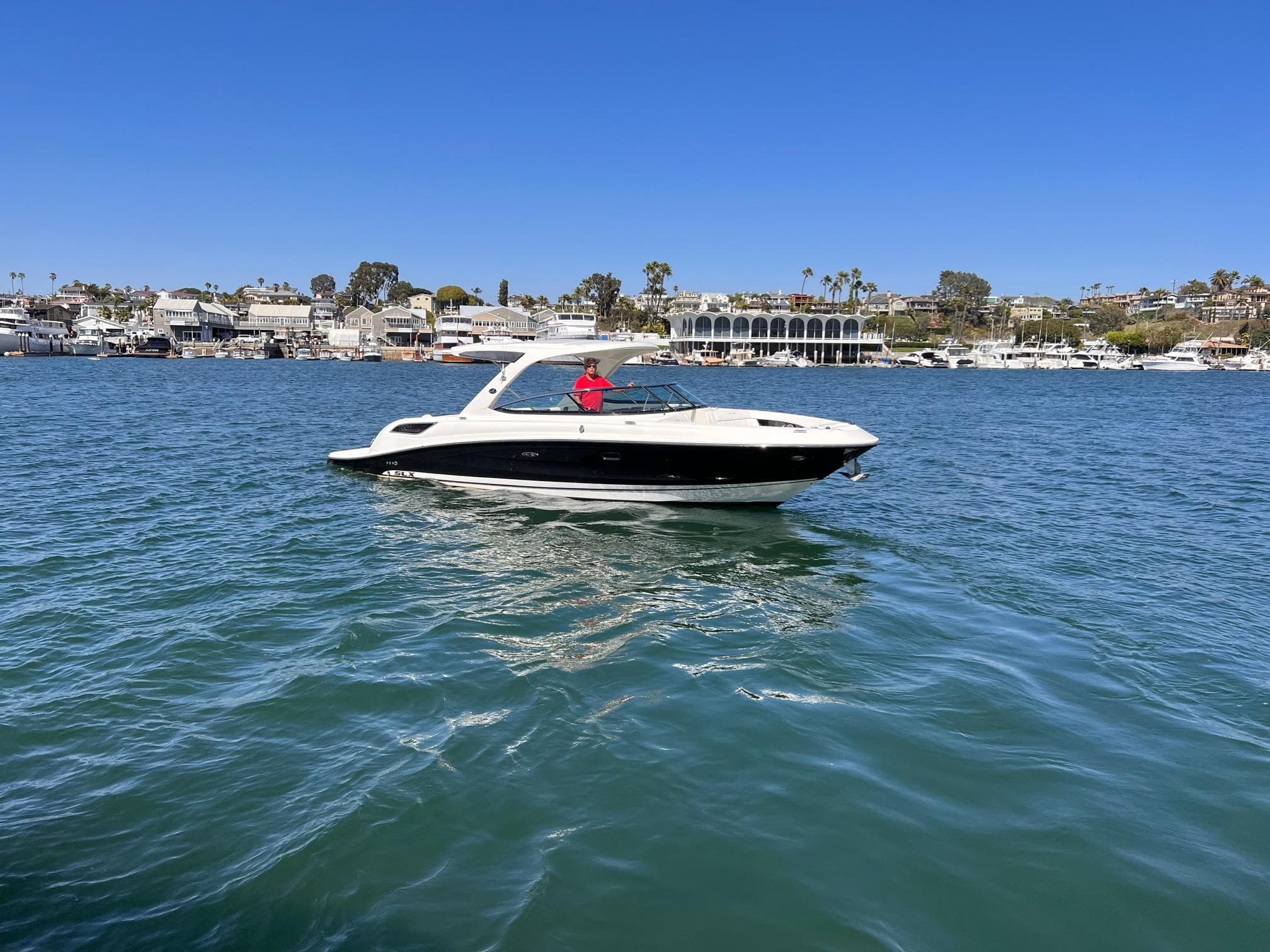 2015 Sea Ray SLX 350 on calm water near coastal town.