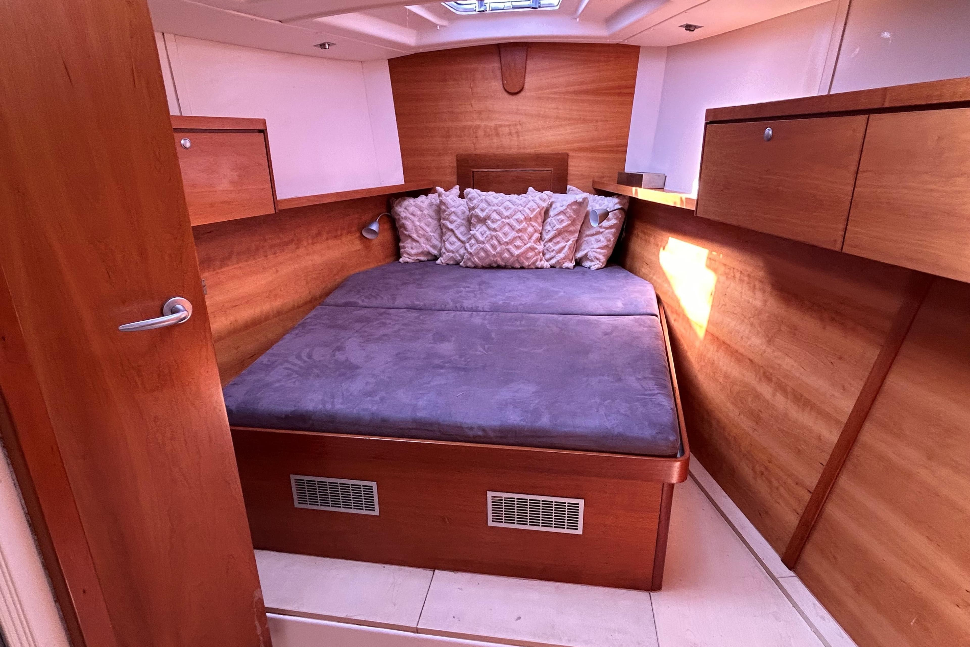 Cozy cabin interior of 2008 Hanse 470e yacht with wooden finish and plush bedding.