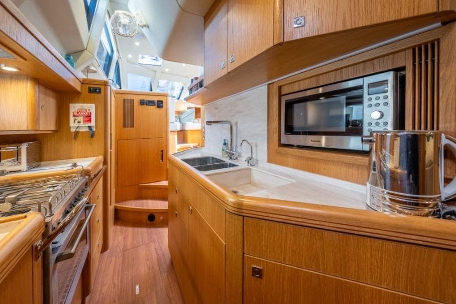 Modern kitchen interior of 2021 Discovery 58 yacht with wood finish and appliances.