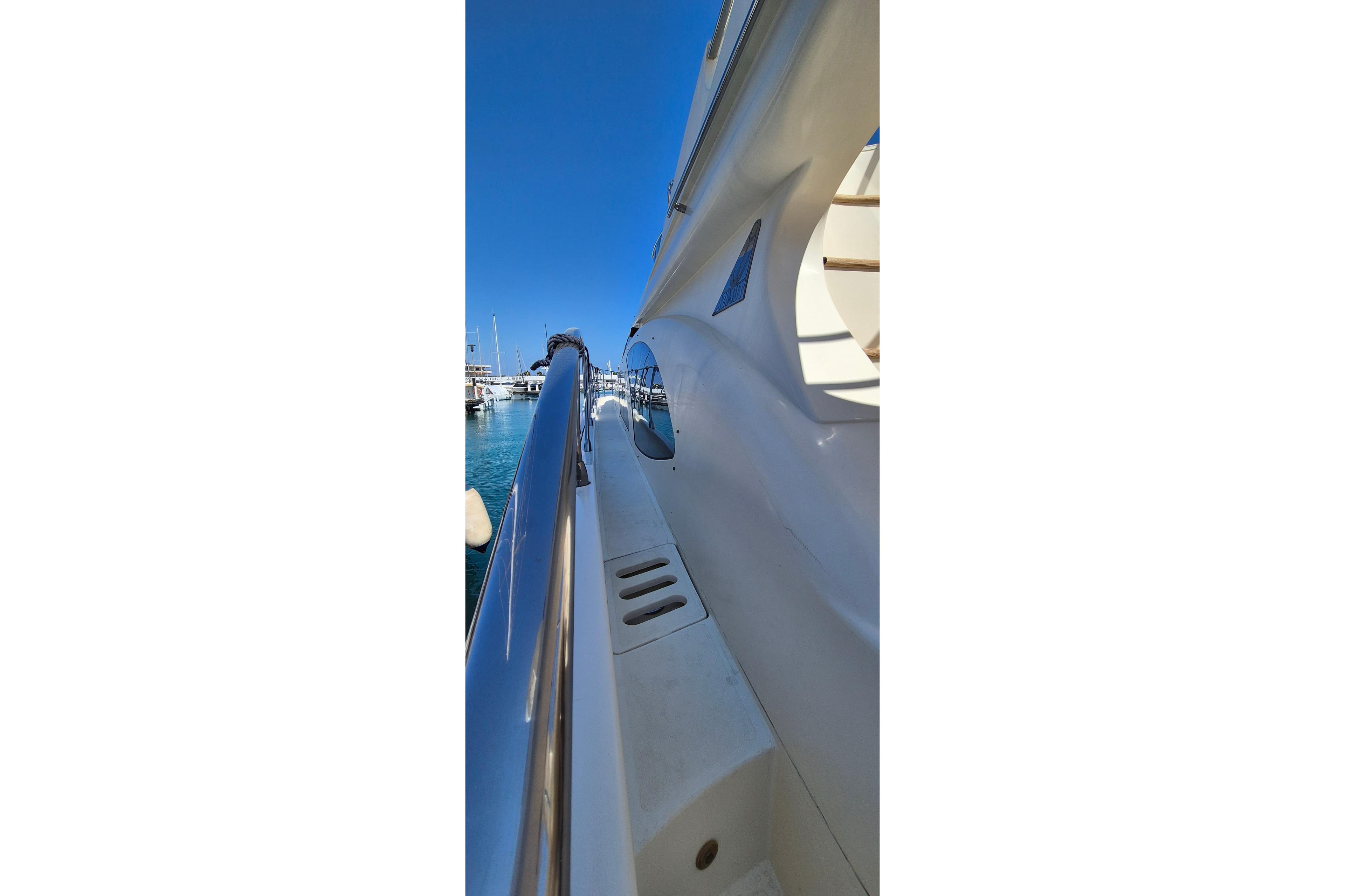 Side view of 2003 Azimut 62 yacht with sleek white design and blue sky.