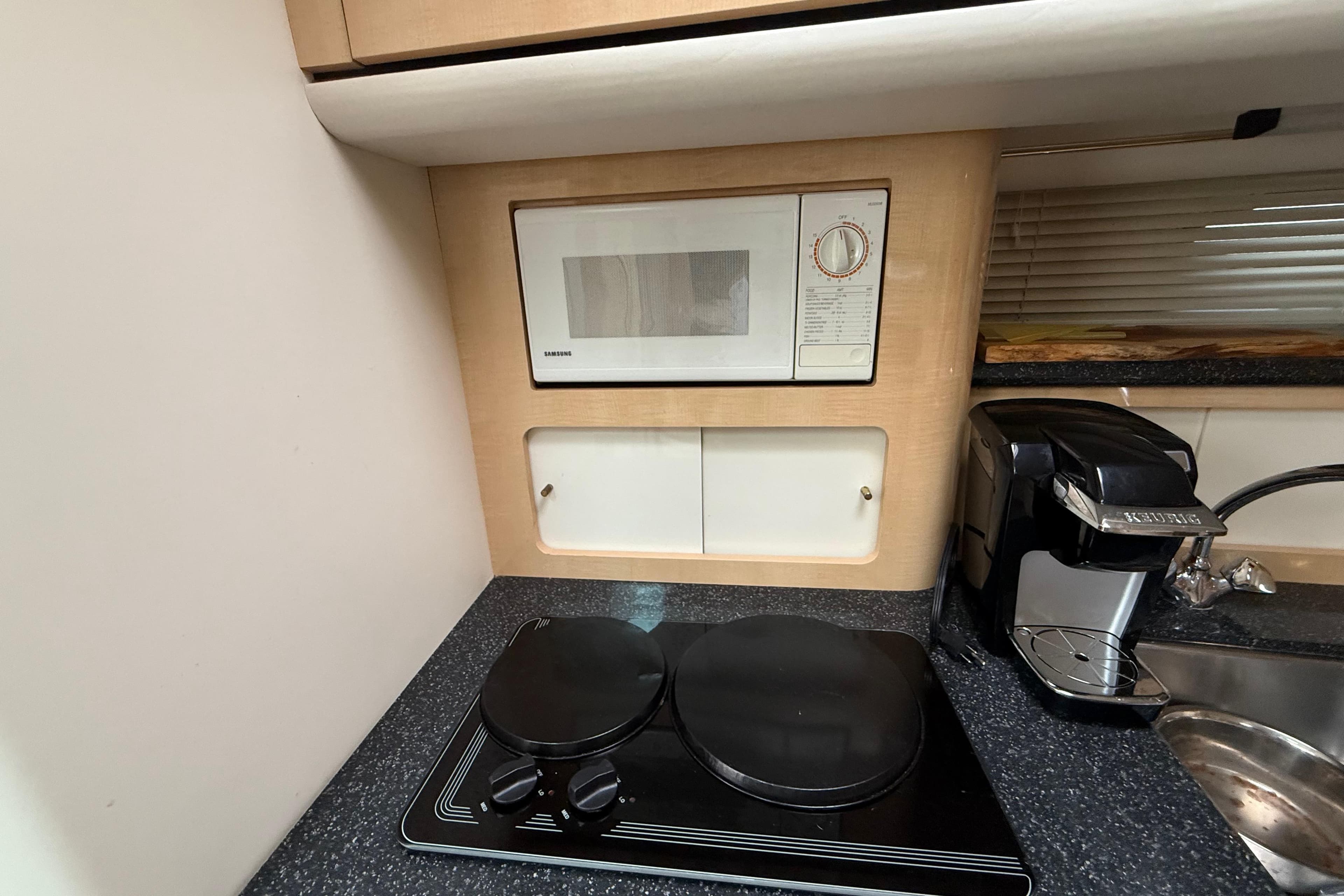Compact kitchen in 2000 Maxum 3700 SCR yacht with microwave, stove, and coffee maker.