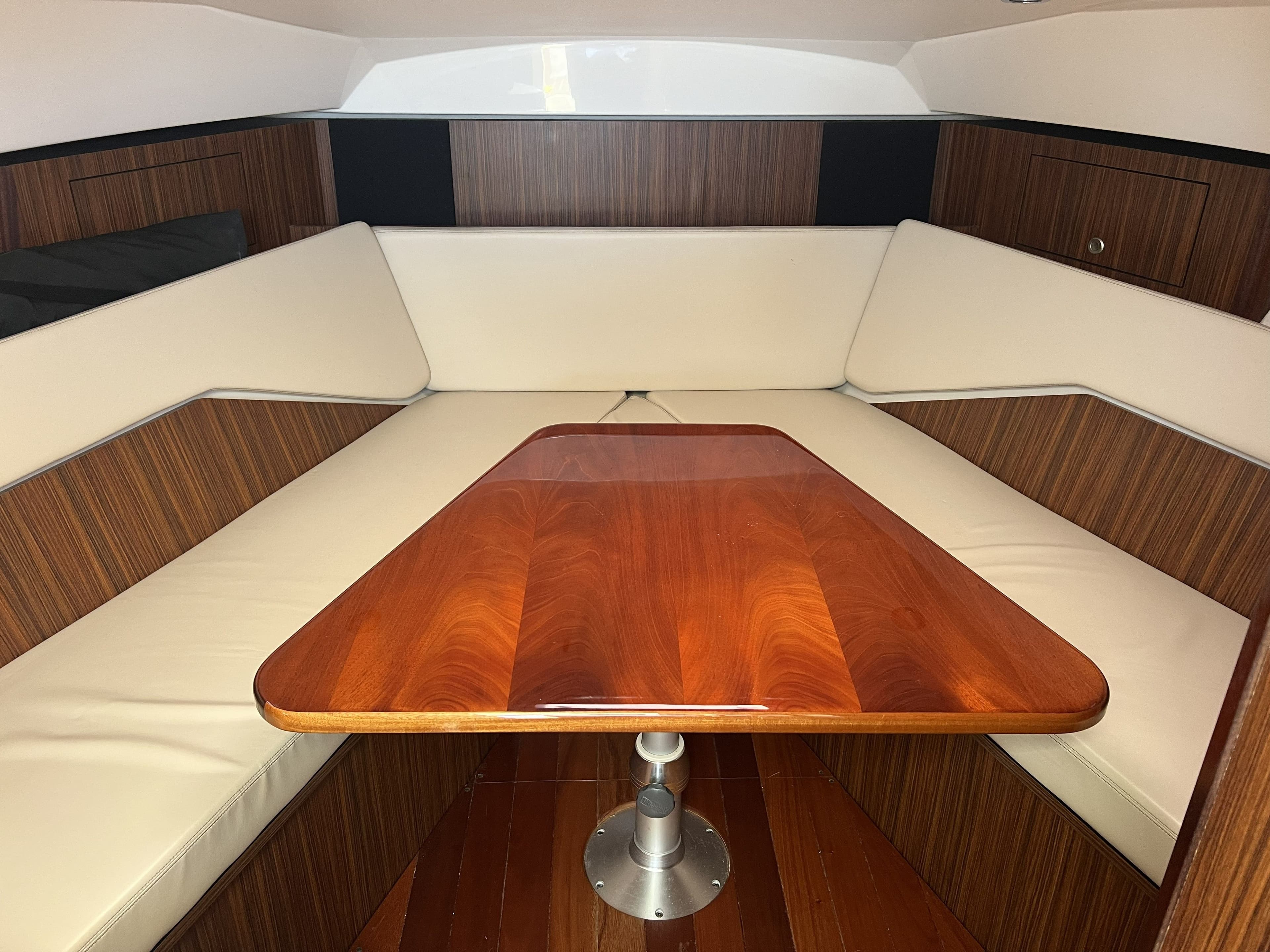 Interior of 2015 Pursuit 325 OS Offshore with wooden table and cushioned seating.