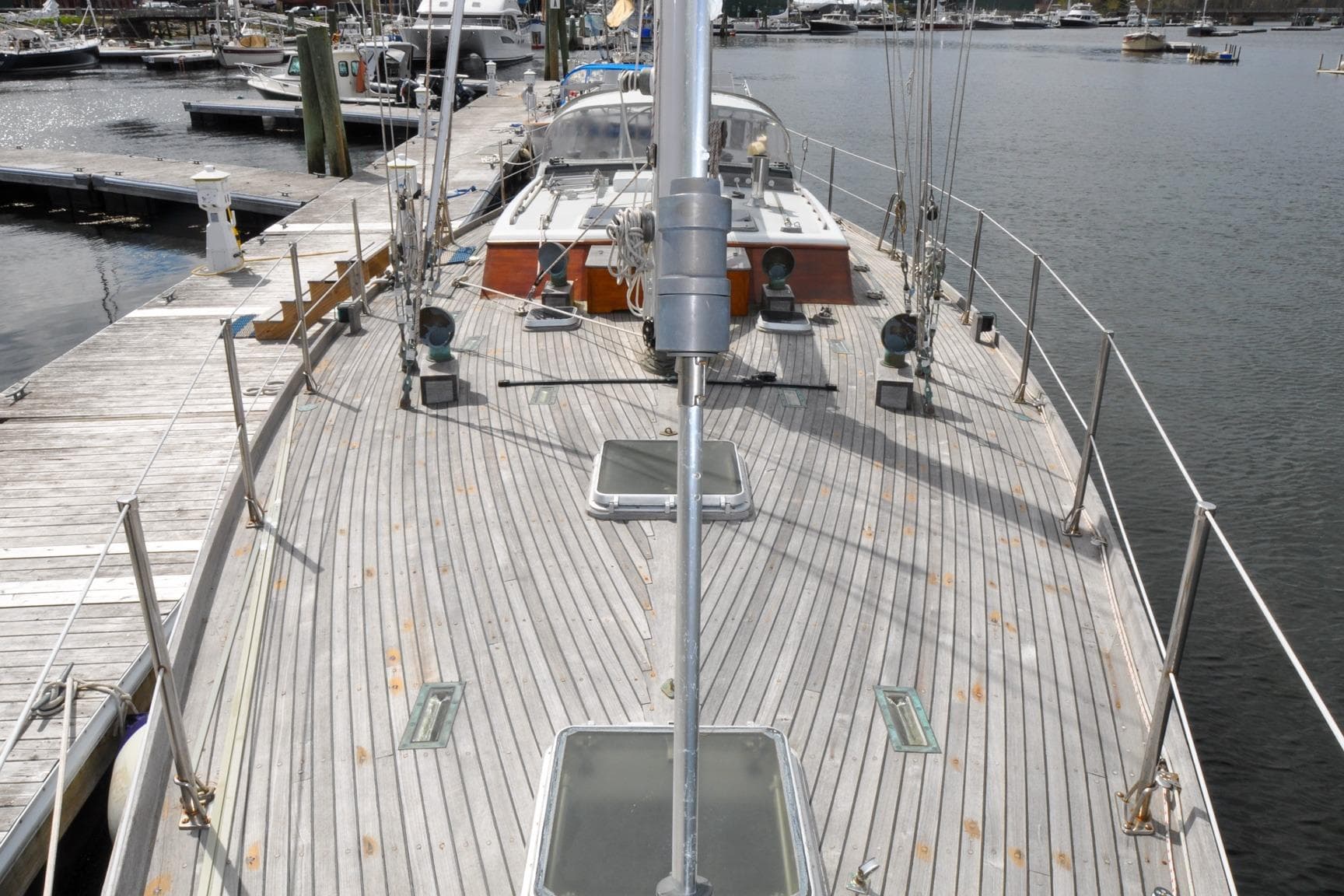 1987 Custom Wittholtz/Luzier Sloop/Cutter docked, showcasing wooden deck and marina backdrop.