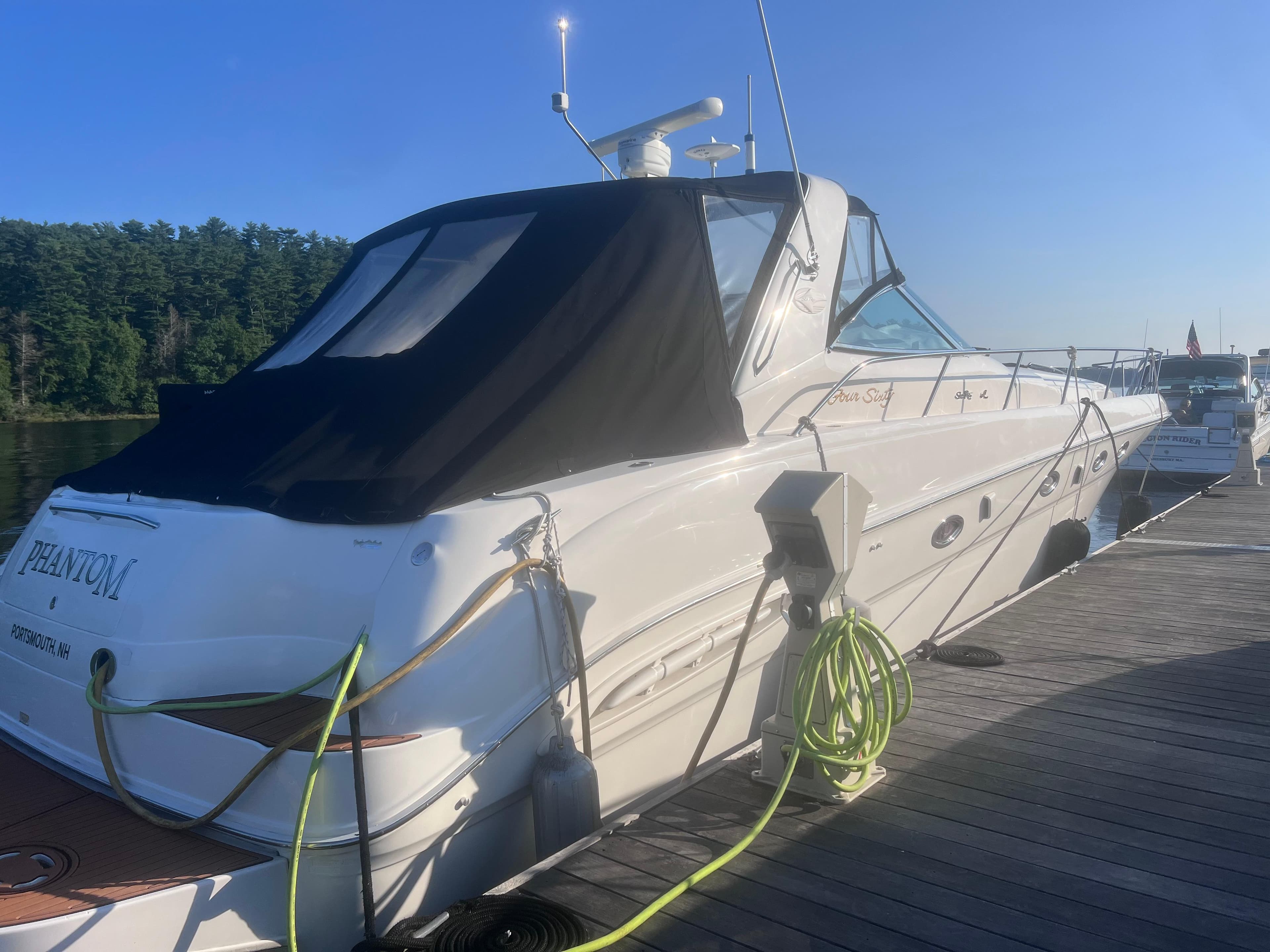 2000 Sea Ray 460 Sundancer yacht docked with black canopy and green hose.