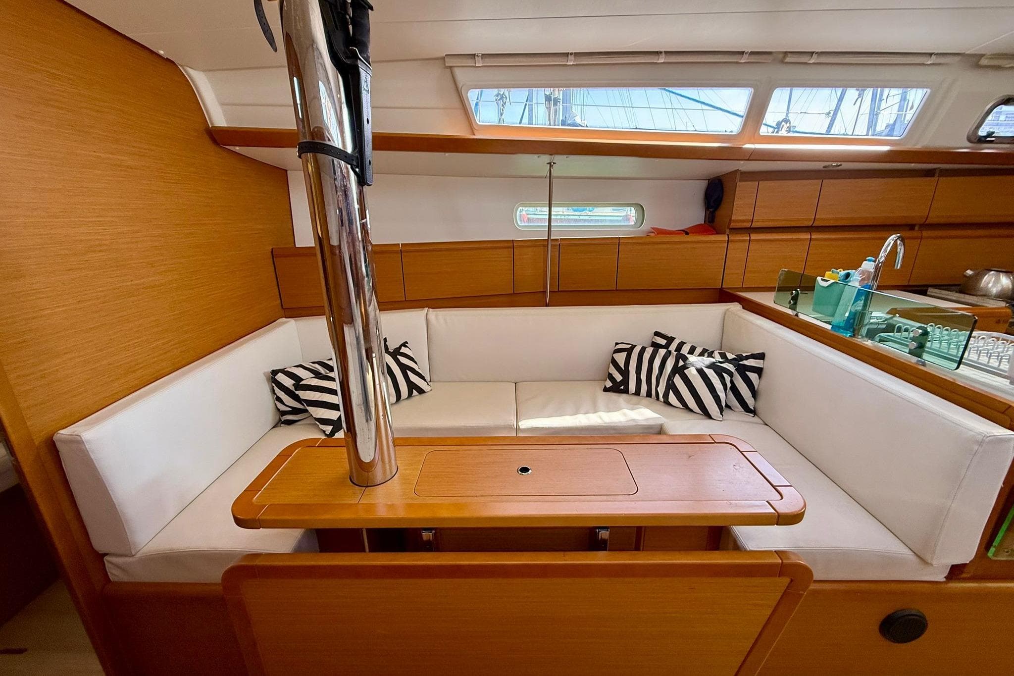 Interior of 2018 Jeanneau Sun Odyssey 389 sailboat with cozy seating and striped cushions.
