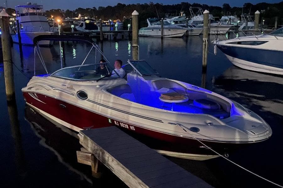 2006 Sea Ray 240 Sundeck boat docked at night with blue interior lighting.