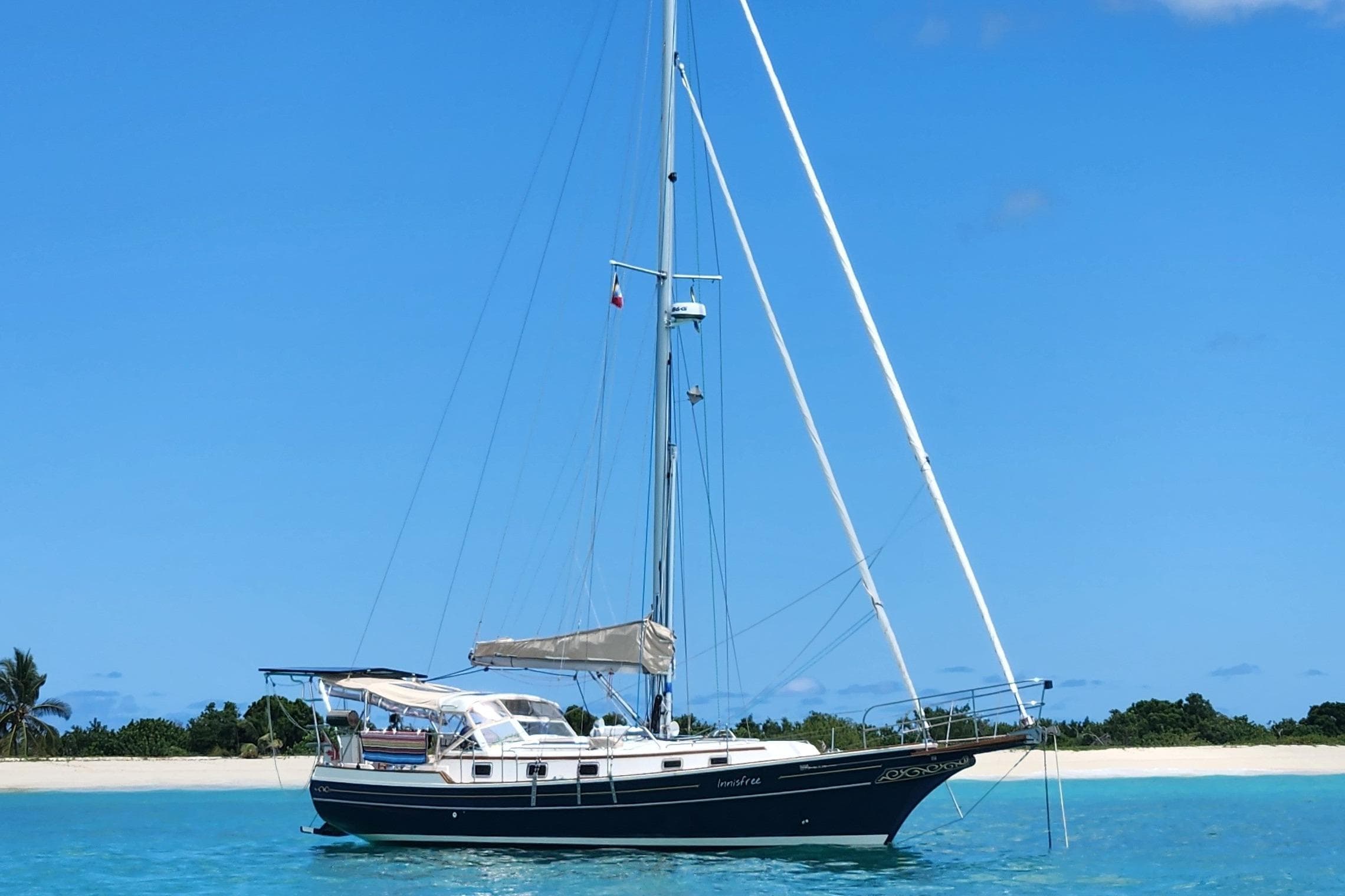 Sailboat Gozzard 36E 1998 anchored in clear blue water near a sandy beach.