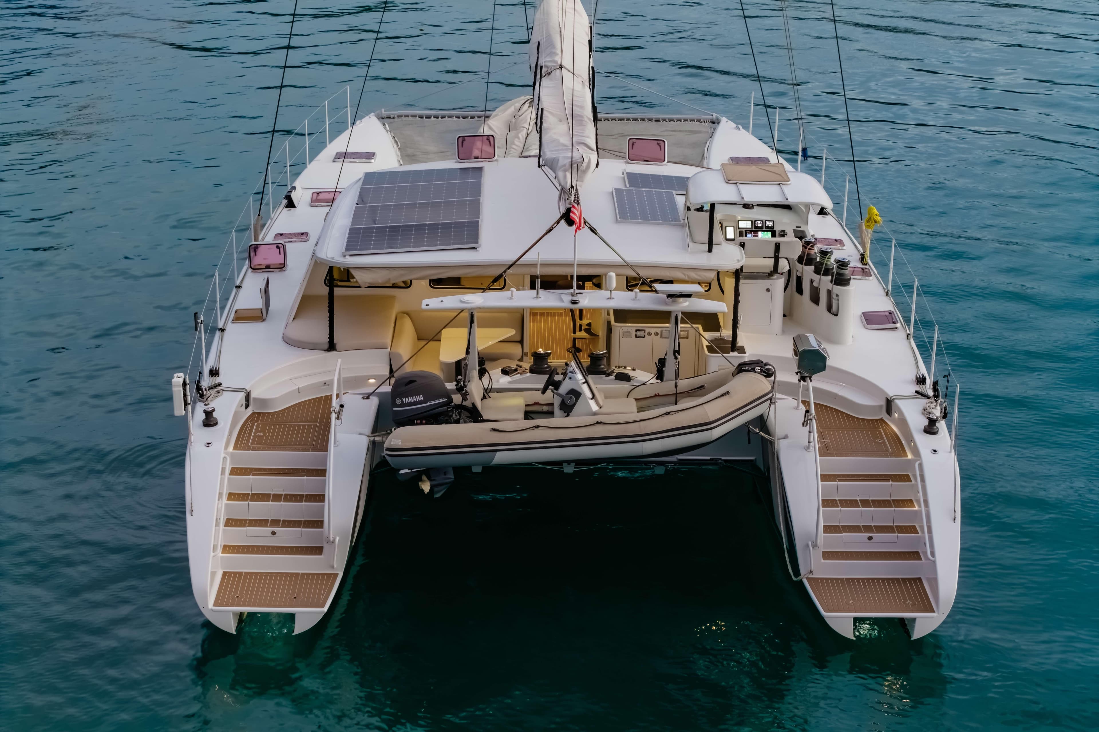 2012 Morrelli & Melvin 65 custom catamaran with solar panels and tender, docked on calm water.