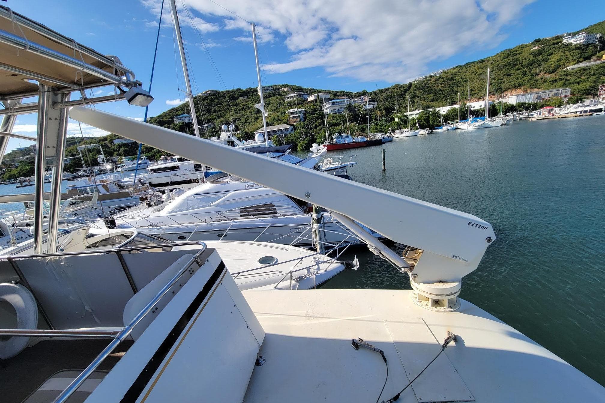 1982 Hatteras 56 Wide Body yacht docked in a scenic marina with surrounding hills.