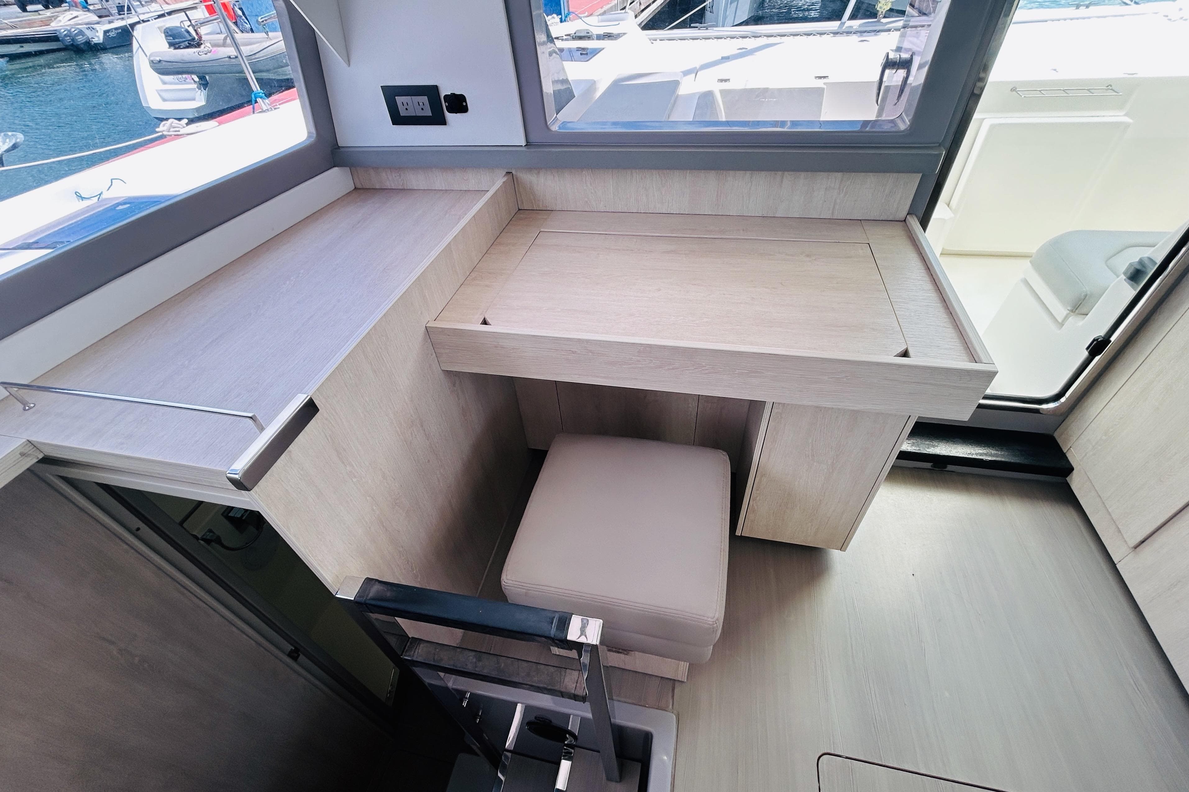 Modern interior of 2021 Leopard 45 yacht with sleek wooden desk and cushioned seat.