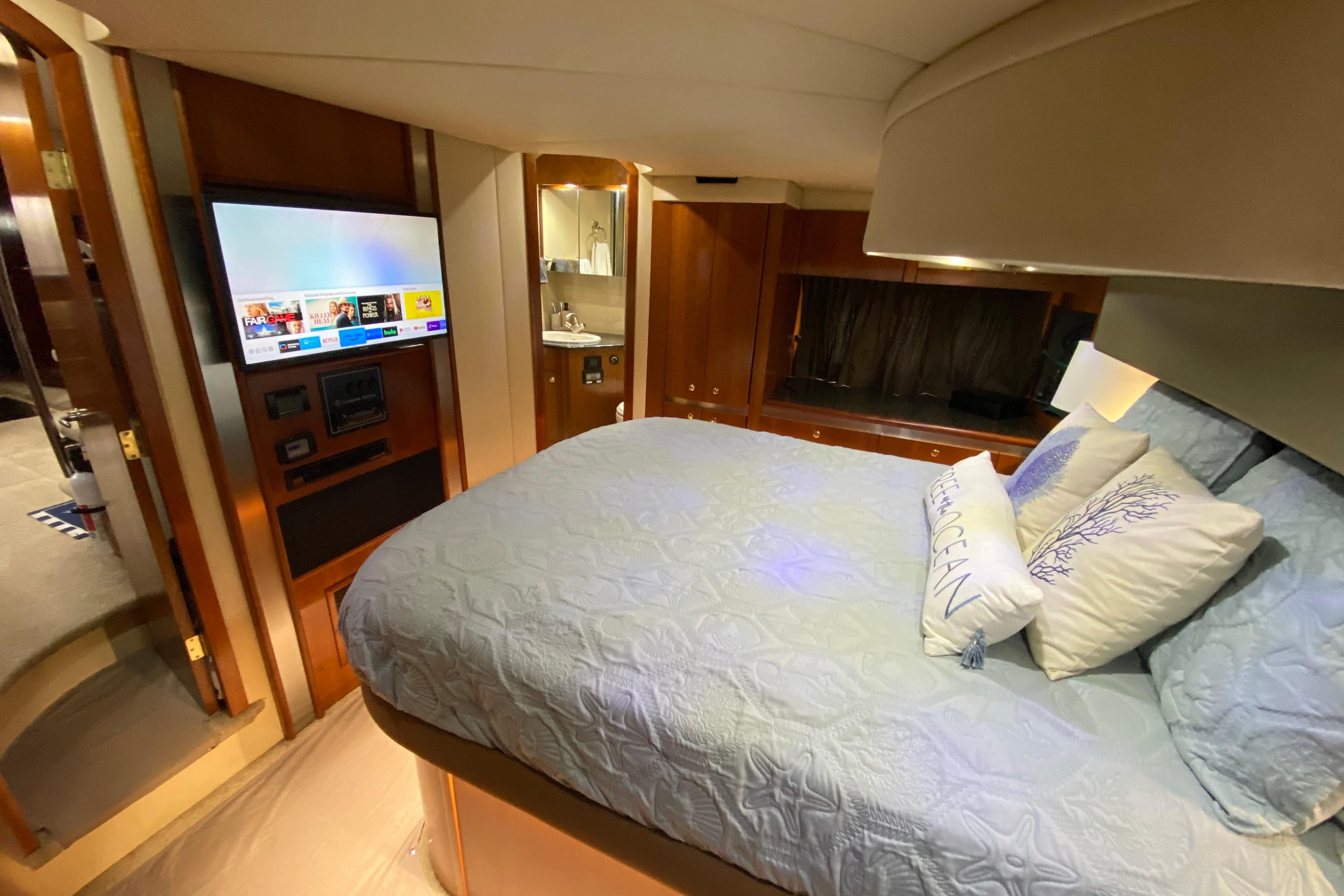 Luxurious 2006 Cruisers Yachts 520 Express cabin with bed, TV, and ensuite bathroom.