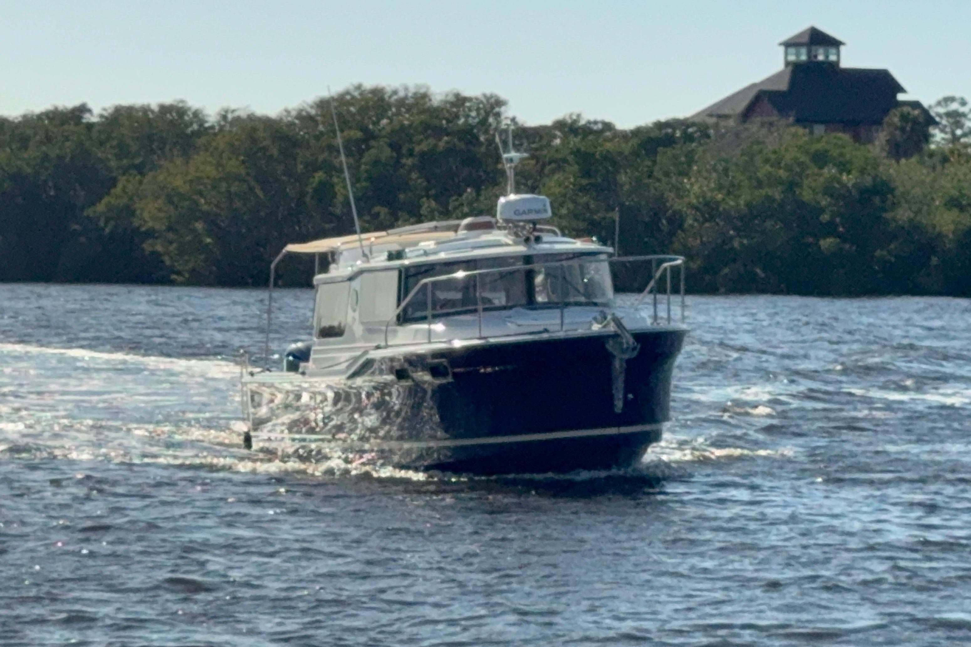 2022 Ranger Tugs R-27 cruising on a scenic river with lush greenery.