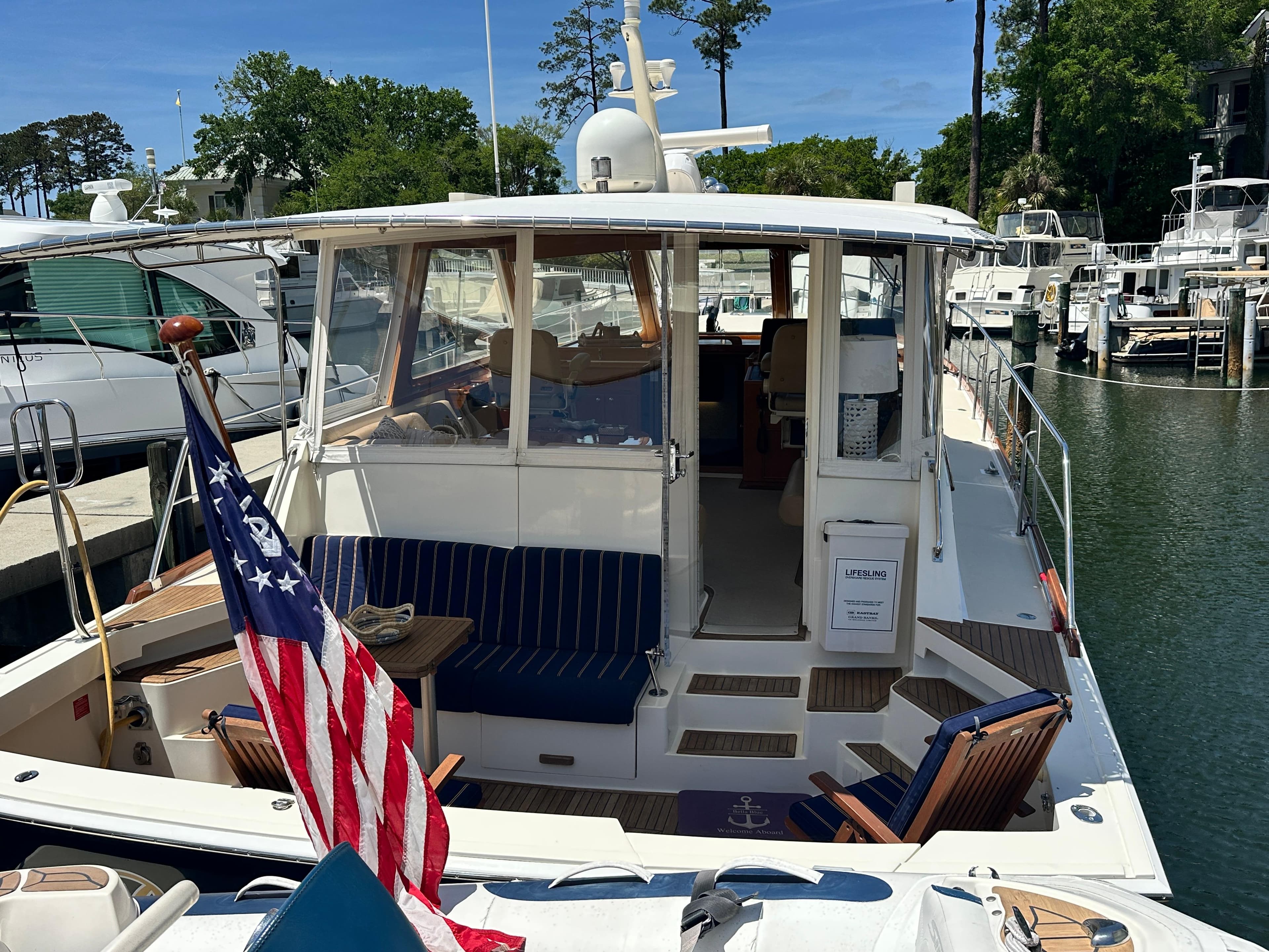 2004 Grand Banks 49 Eastbay HX yacht docked, featuring a spacious deck and American flag.
