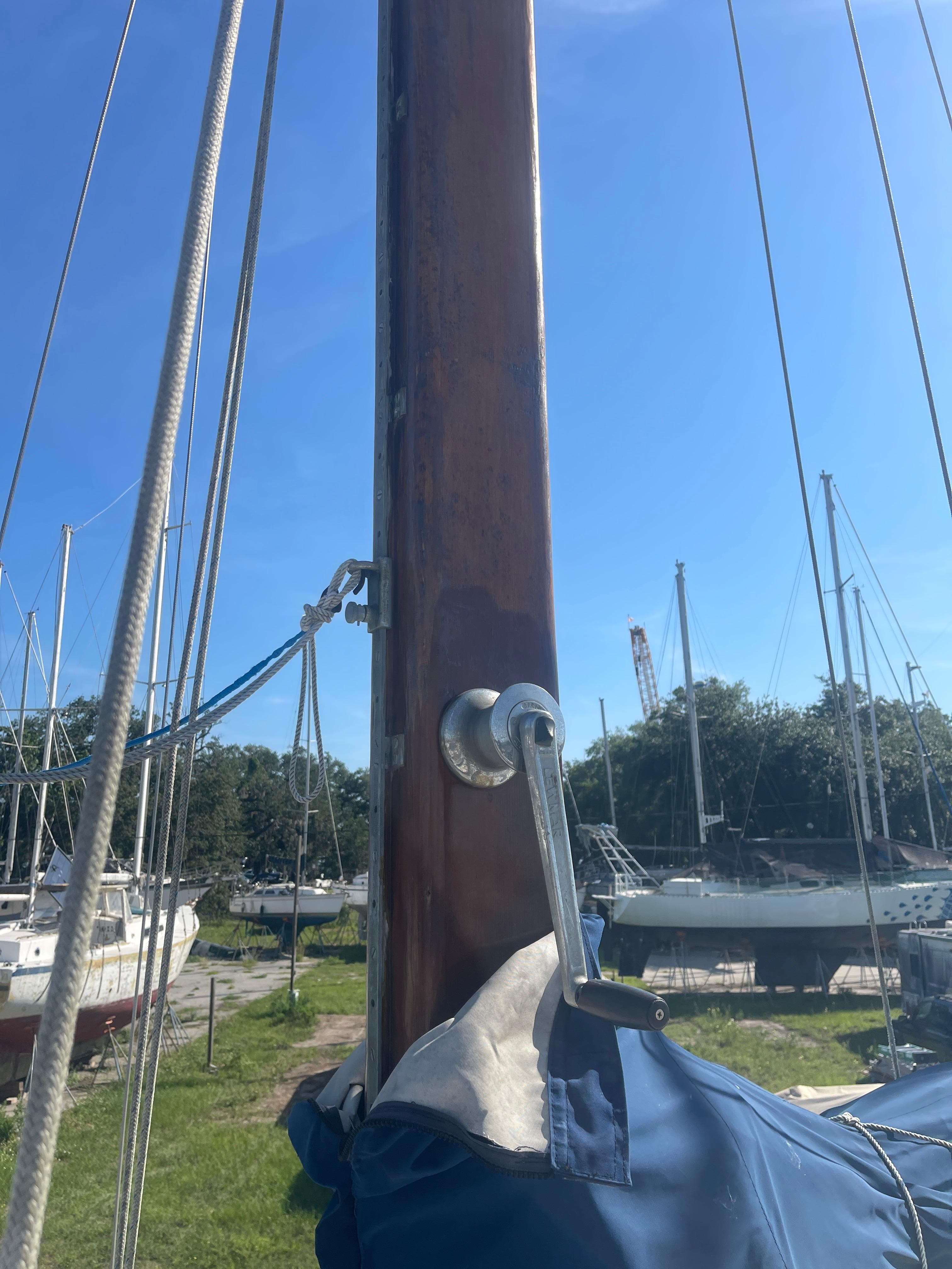 1976 Cheoy Lee Clipper 42 sailboat mast with winch handle, docked under clear blue sky.