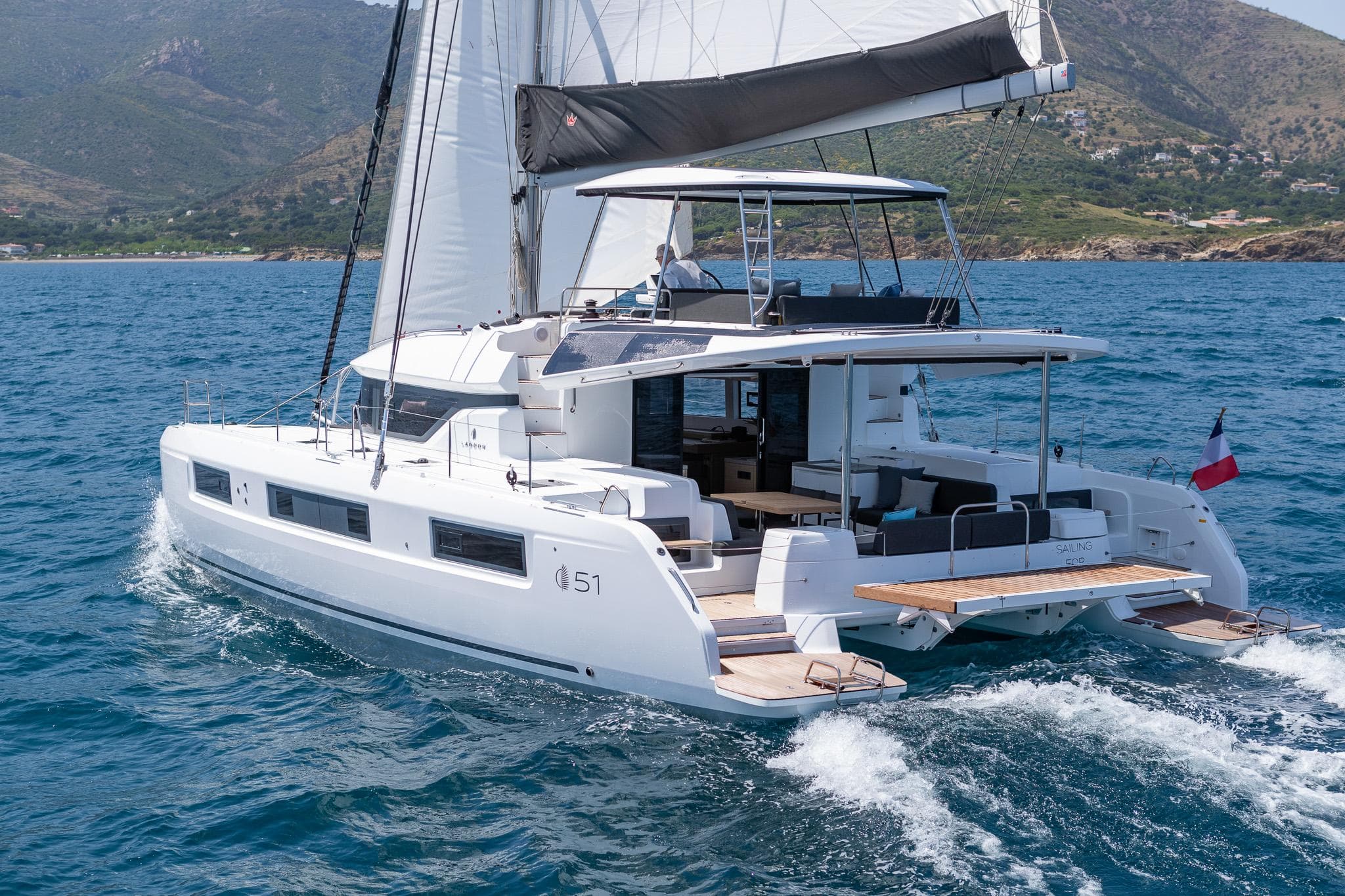 2025 Lagoon 51 ICONIC catamaran sailing on open water, showcasing sleek design and spacious deck.