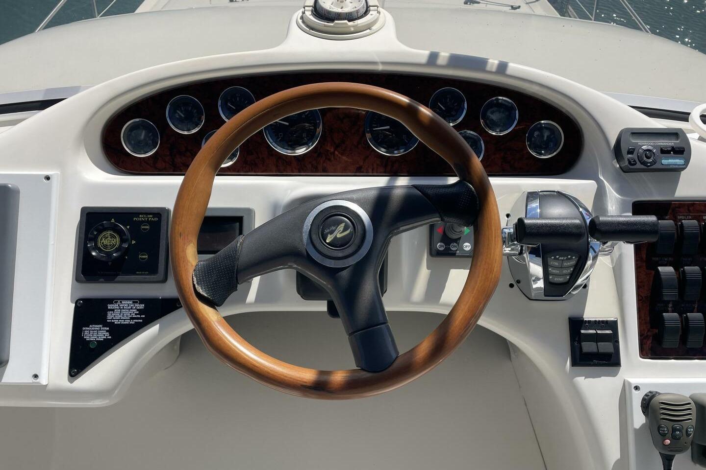 Helm of 2000 Sea Ray 400 Sedan Bridge with wooden steering wheel and control panel.
