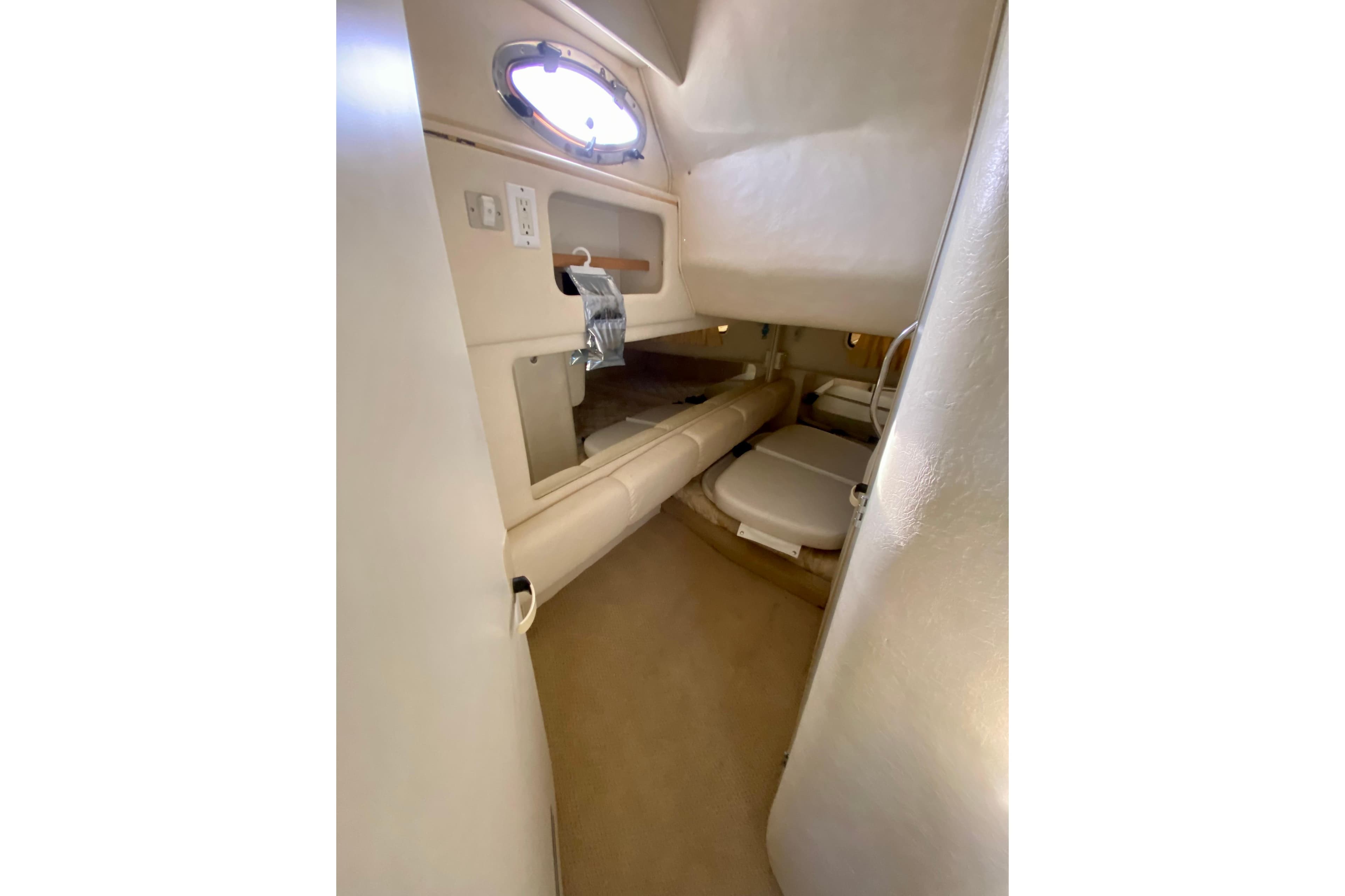 1998 Sea Ray Sundancer 310 cabin interior with beige upholstery and porthole window.