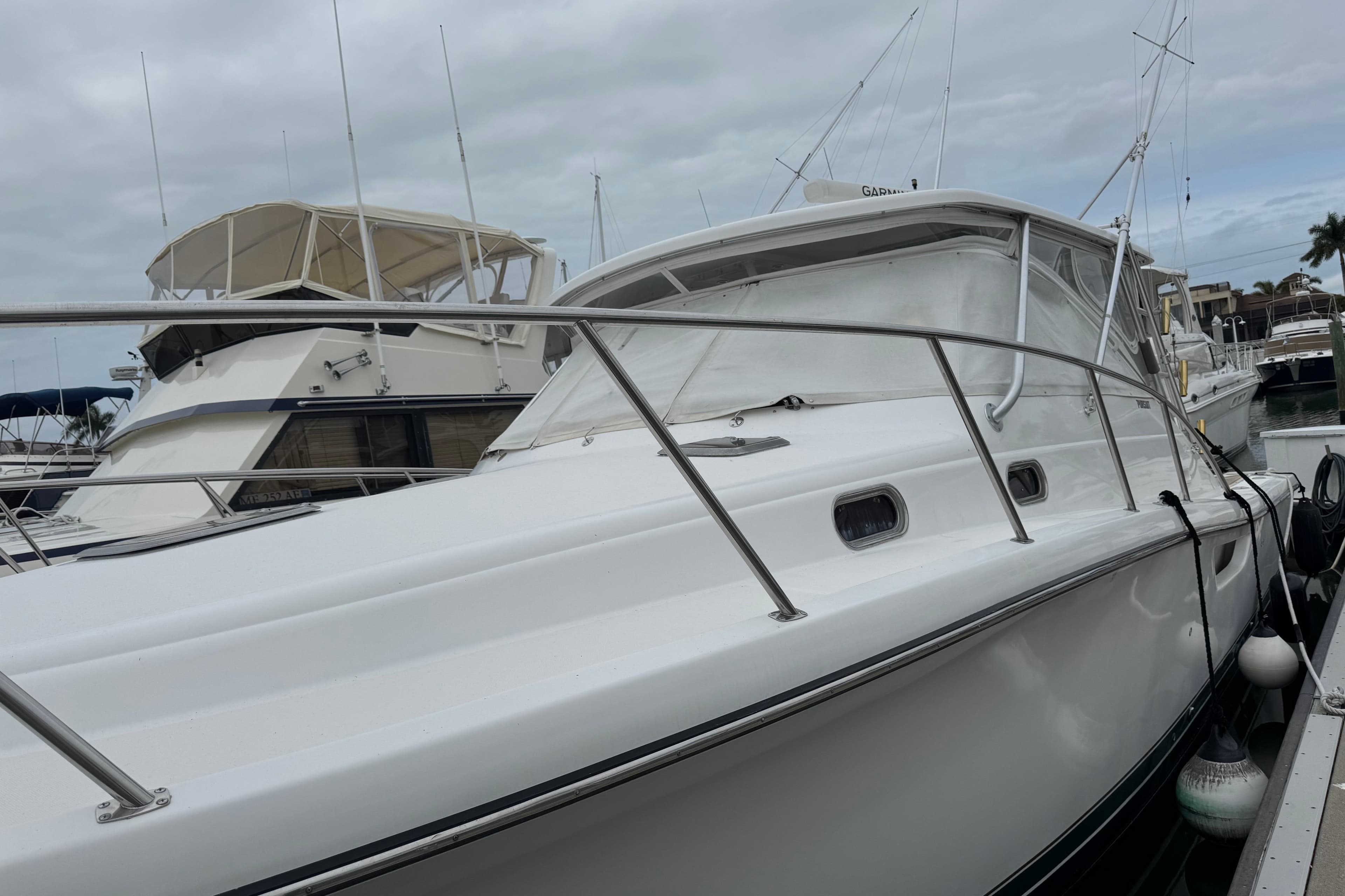 2002 Pursuit 3800 Express yacht docked at marina under cloudy sky.