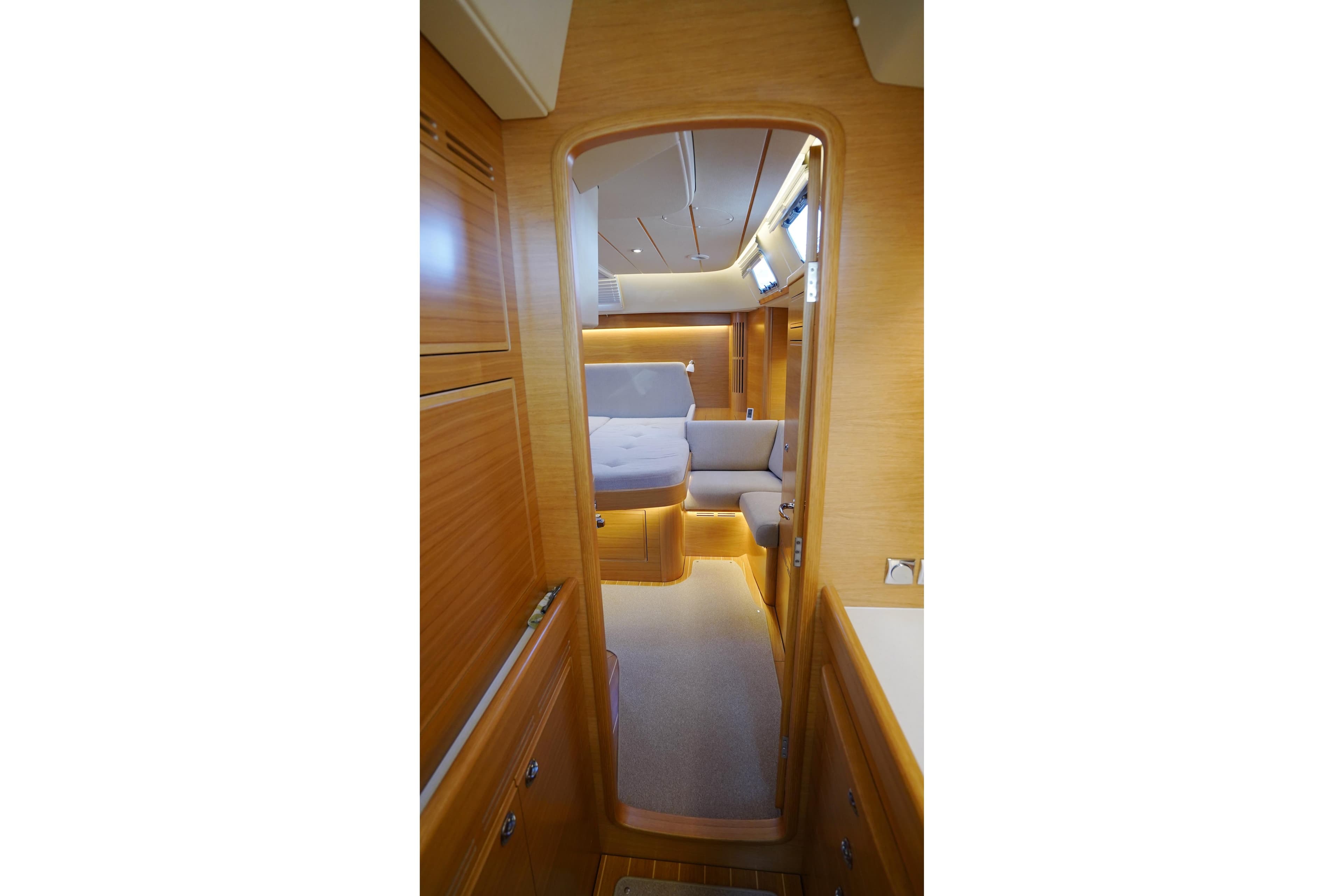 Interior of 2022 Hallberg-Rassy 57 yacht, featuring elegant wood finish and cozy seating area.