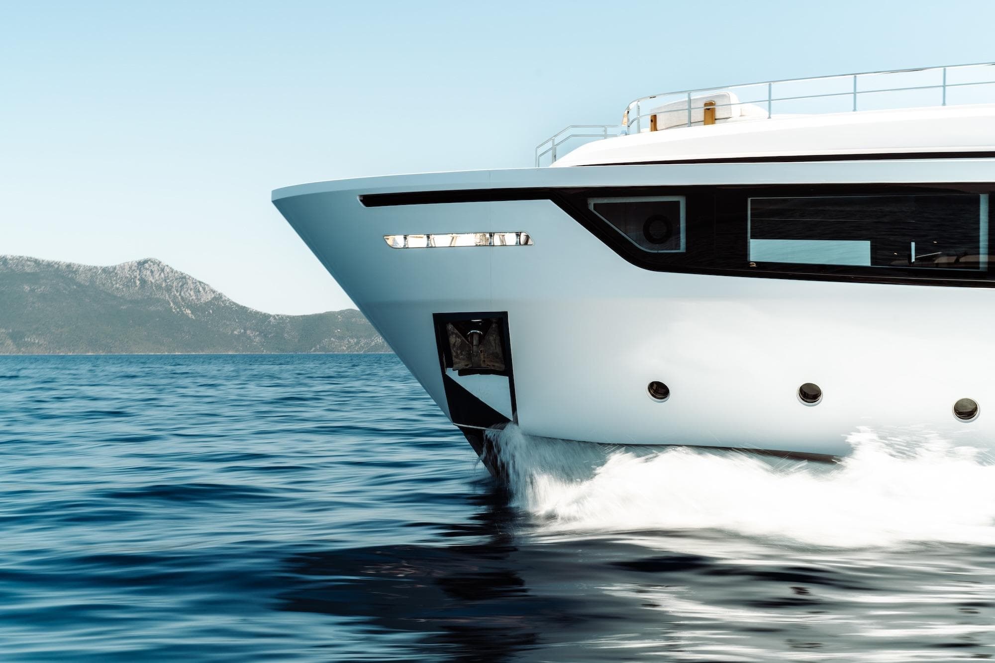 2024 Custom Line Navetta 30 yacht cruising on open sea with mountainous backdrop.