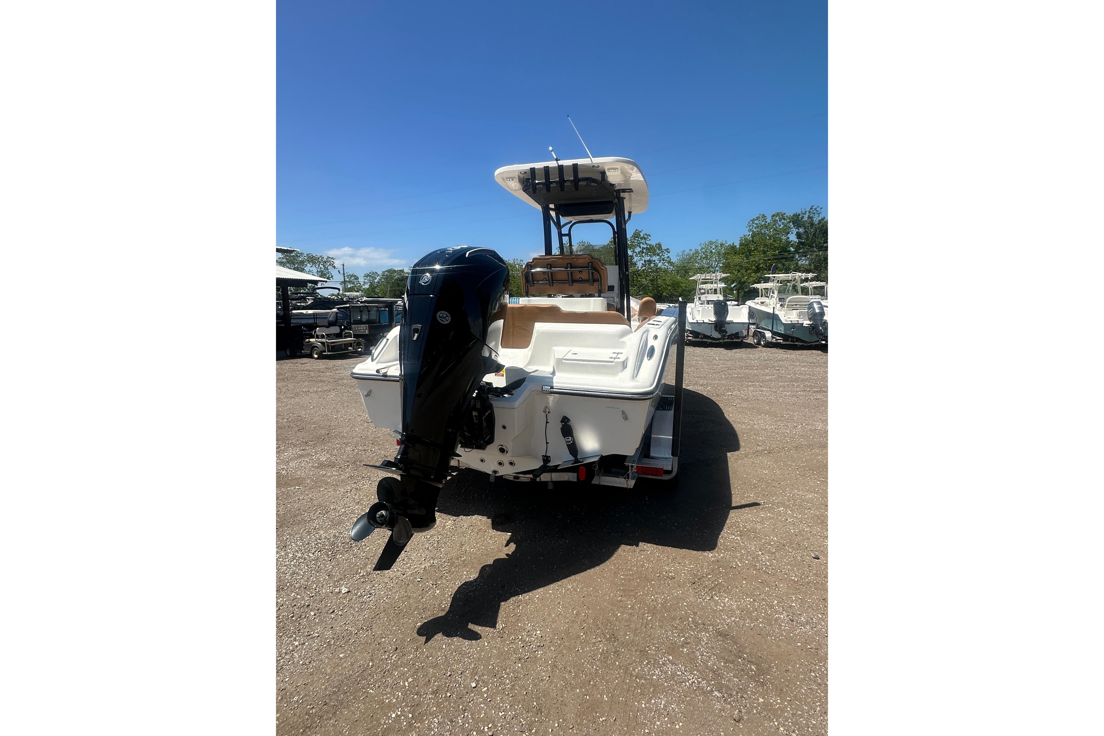 2026 Key West 239 FS boat with outboard motor, parked on gravel lot under clear blue sky.