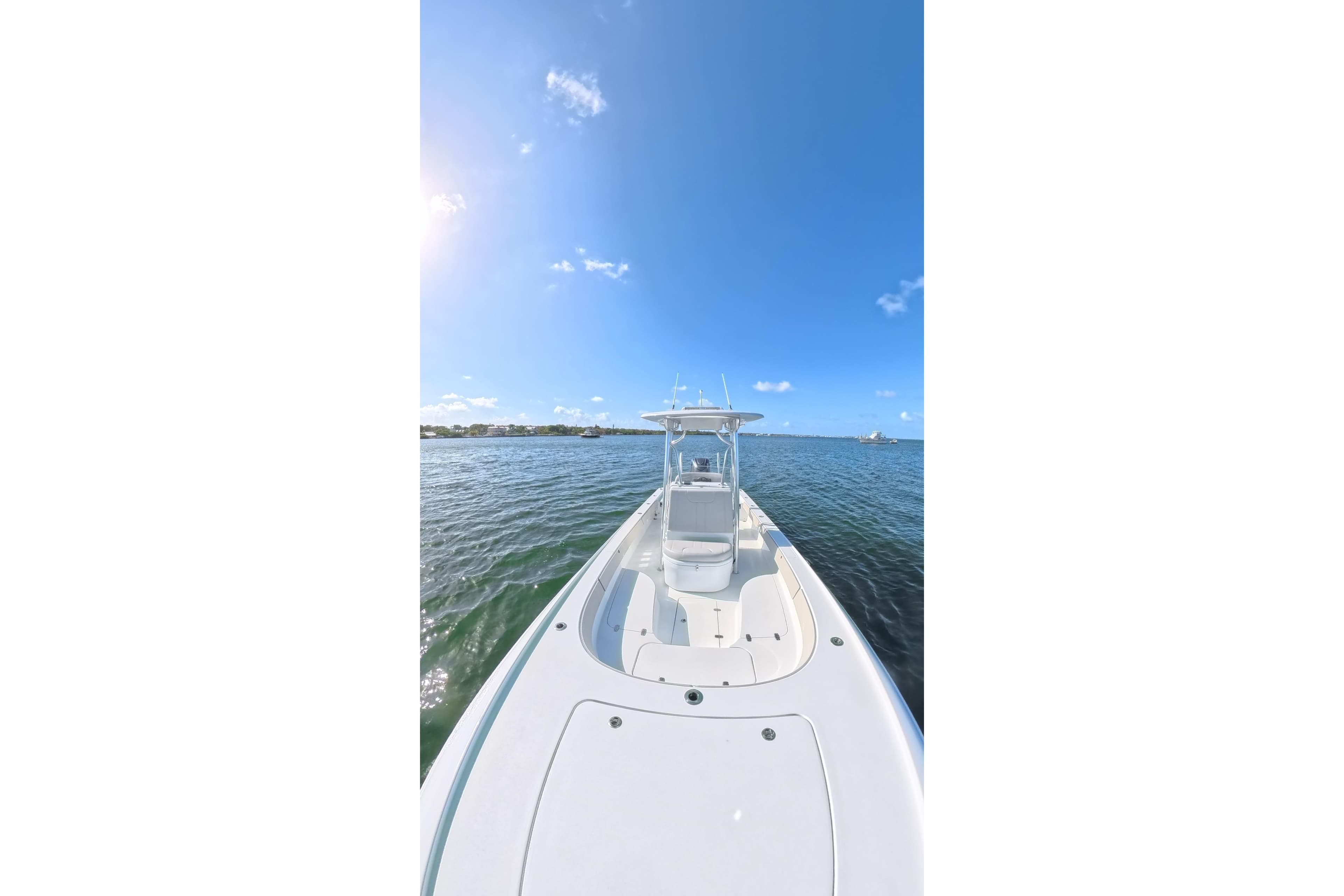 2025 Contender 26 Bay boat on calm water under clear blue sky.