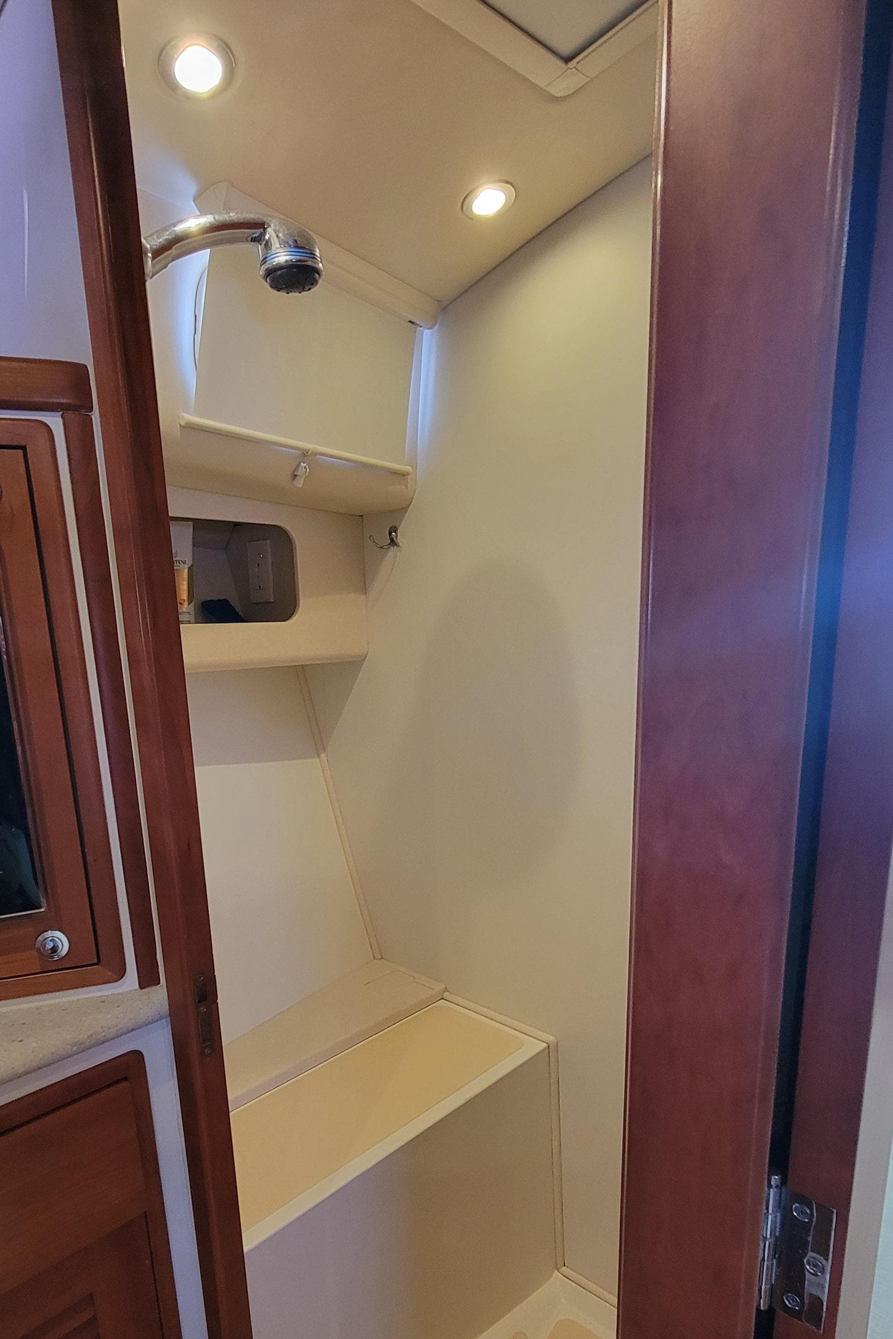 2011 MJM 40z Downeast boat interior shower with wooden accents and built-in shelving.