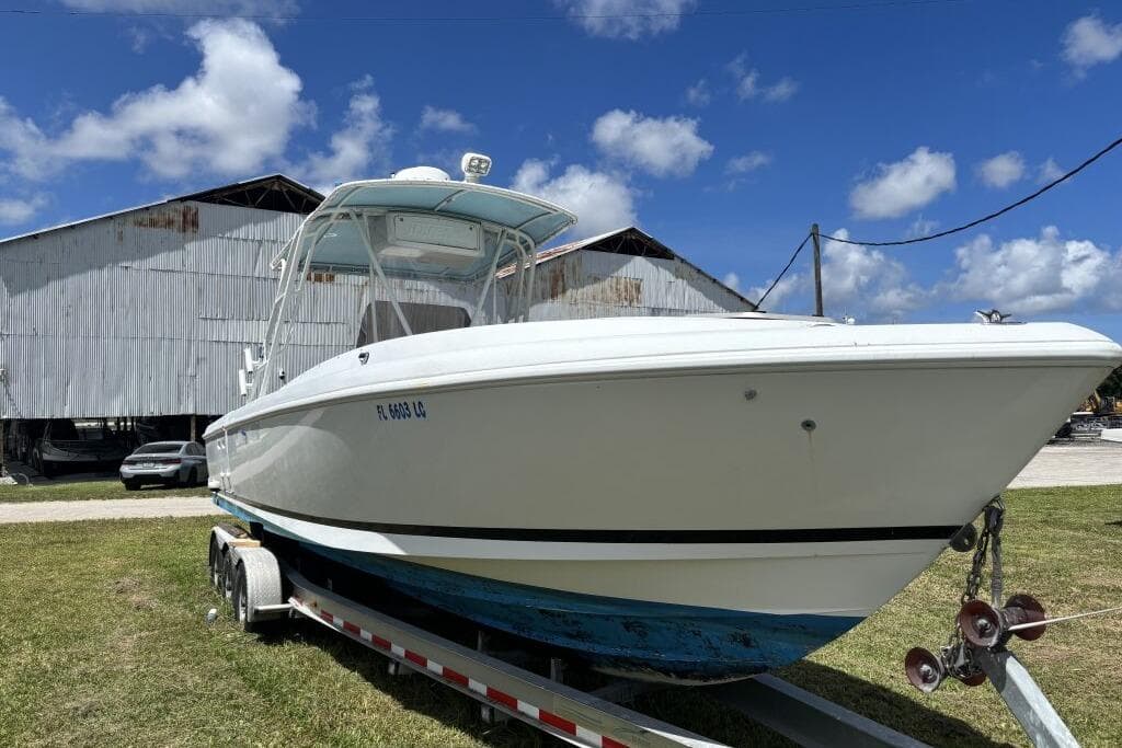 2000 Intrepid 322 Cuddy boat on trailer, parked outdoors under blue sky.