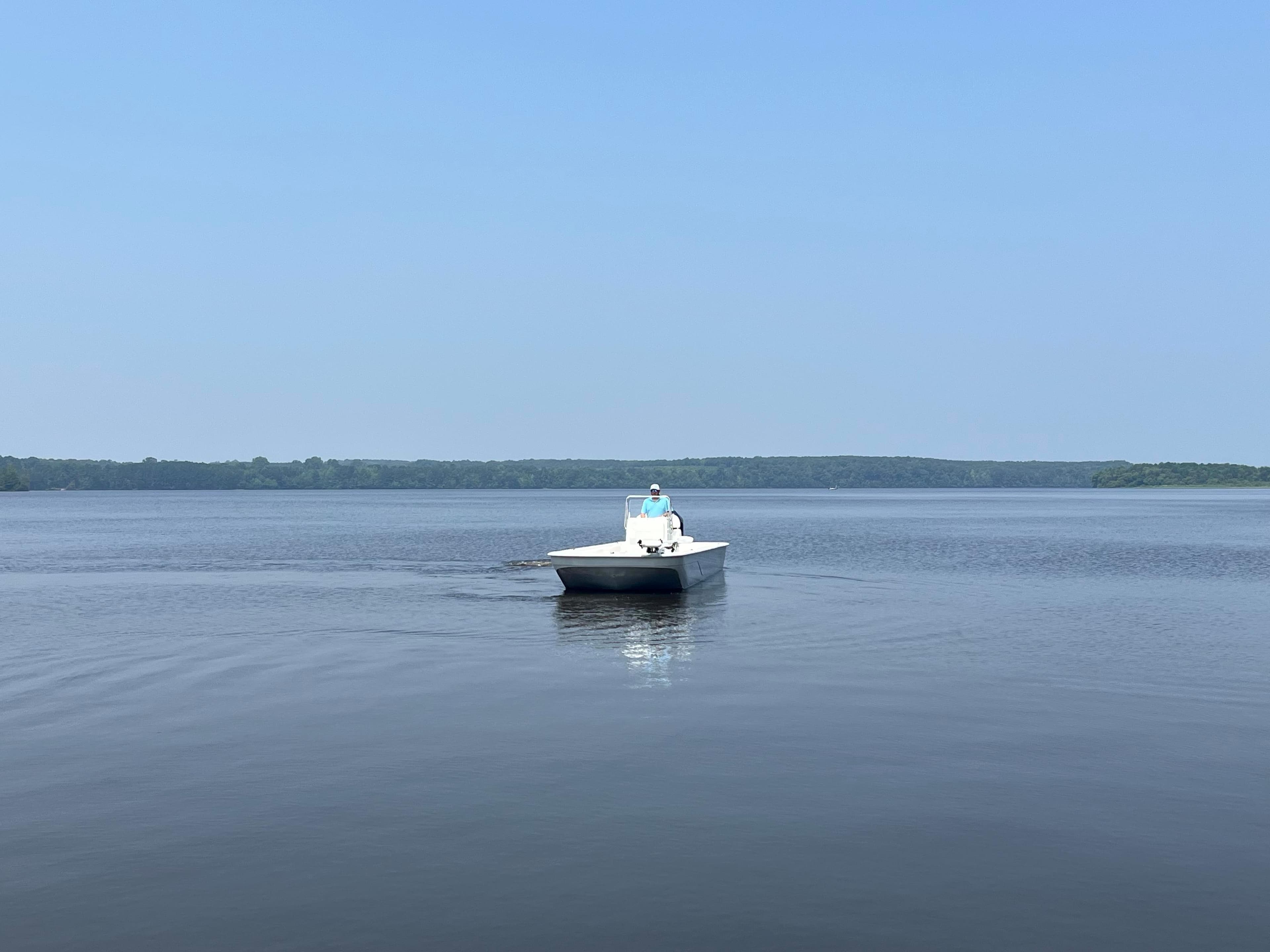 2024 Coastal Skiff 271 on calm lake waters under clear blue sky.