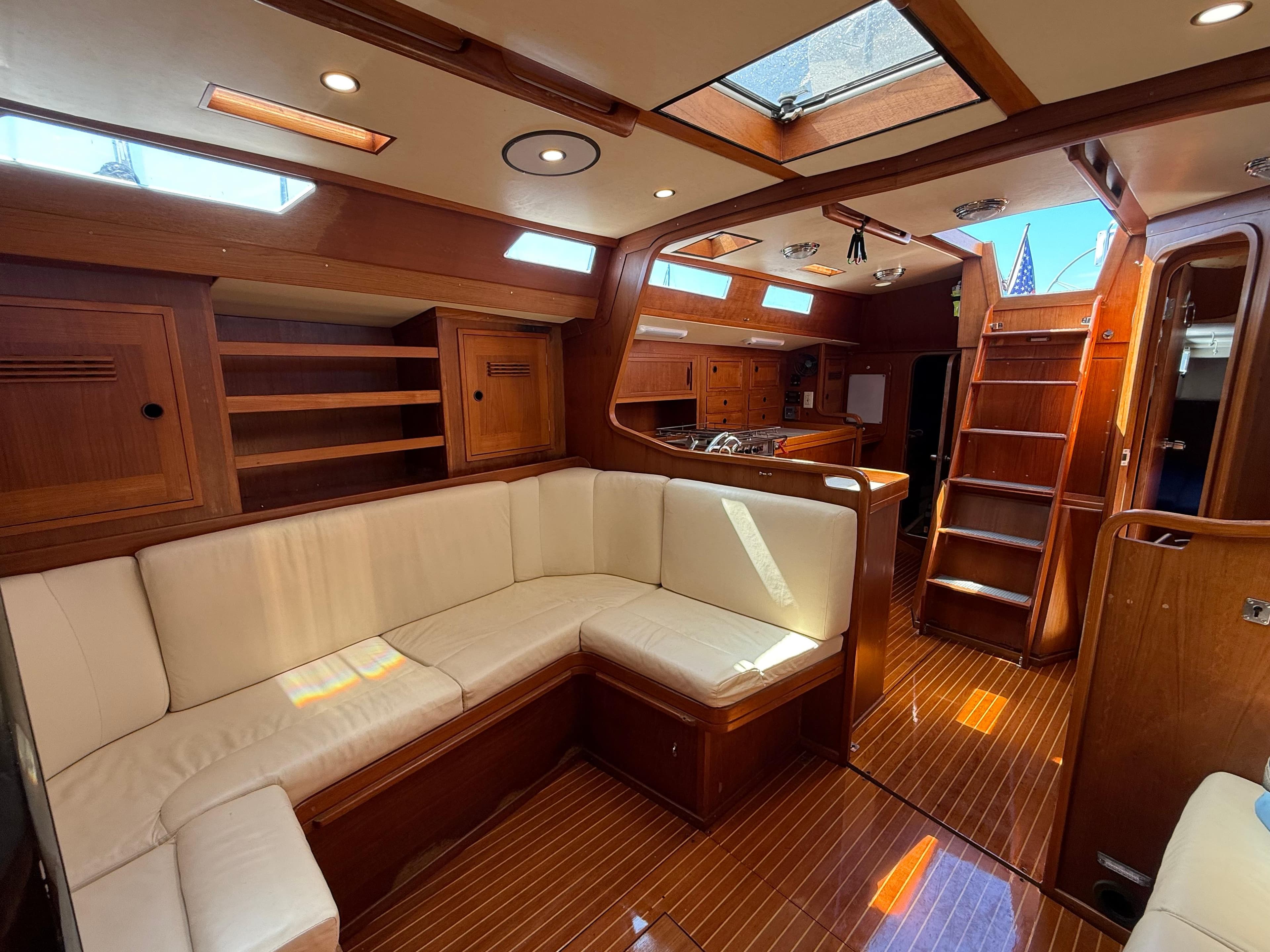 Luxurious interior of 1986 Baltic Custom Farr 44 yacht with wooden finish and white seating.