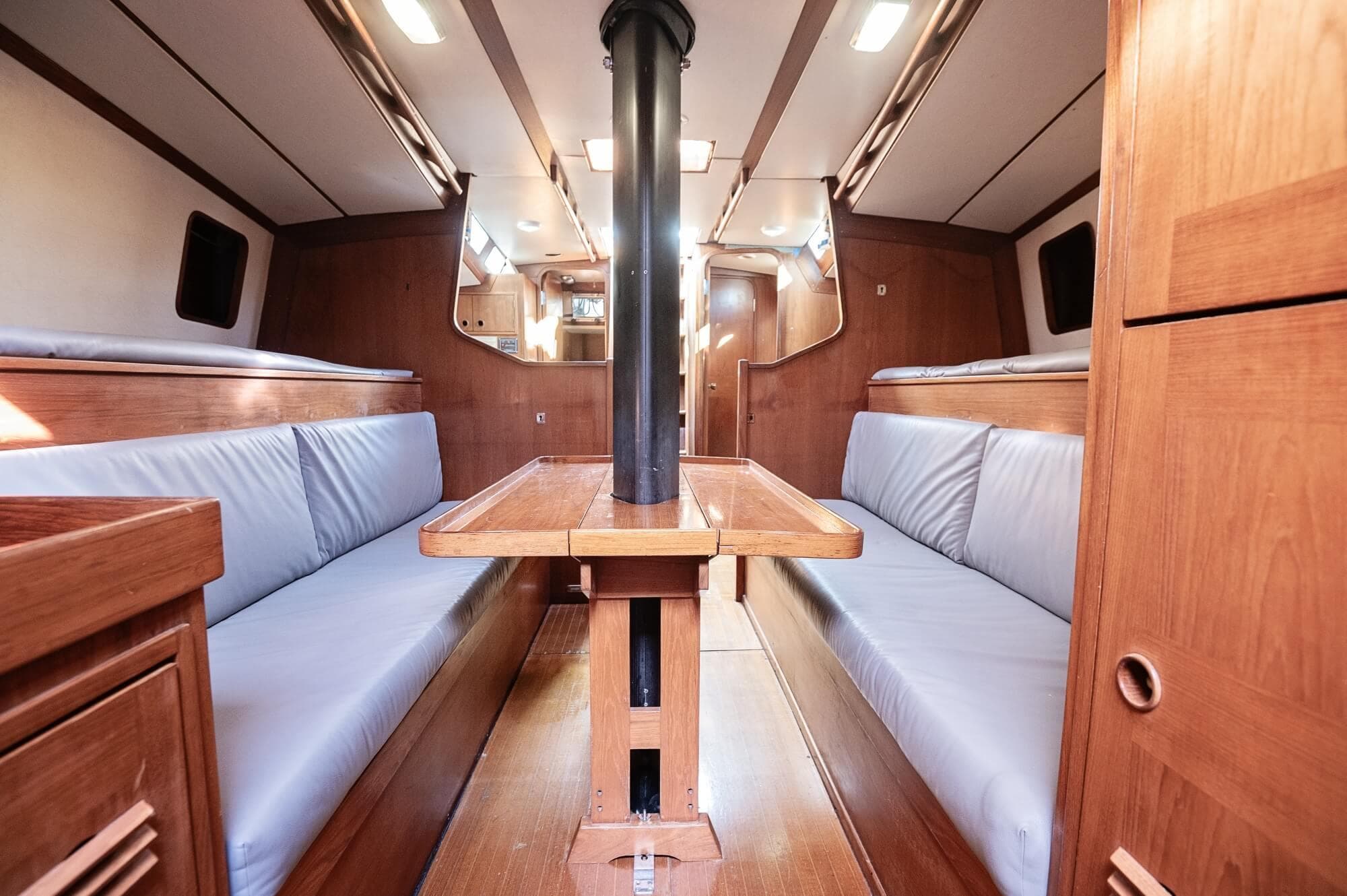 Interior of a 1977 Baltic 42 sailboat with wooden furnishings and blue seating.