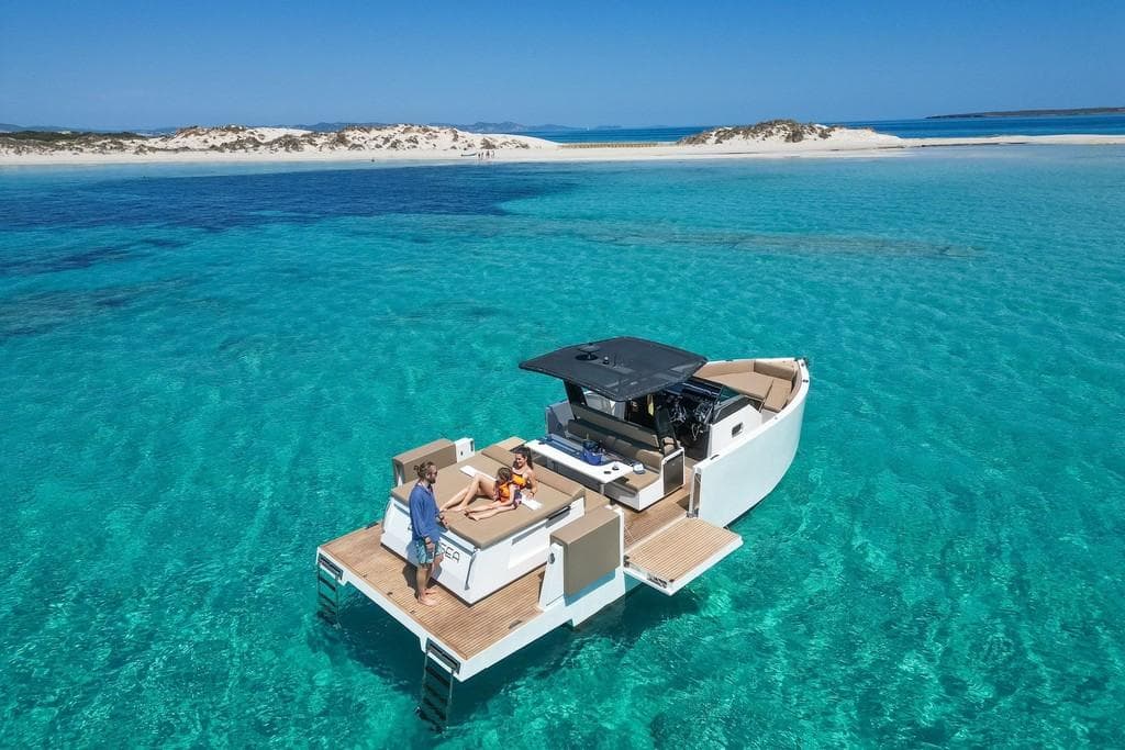 De Antonio Yachts D 33 Open 2018 cruising in clear turquoise waters near sandy beach.