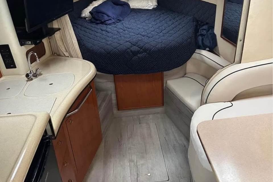 Interior of 2001 Sea Ray 340 Sundancer with cozy bed and compact kitchen area.