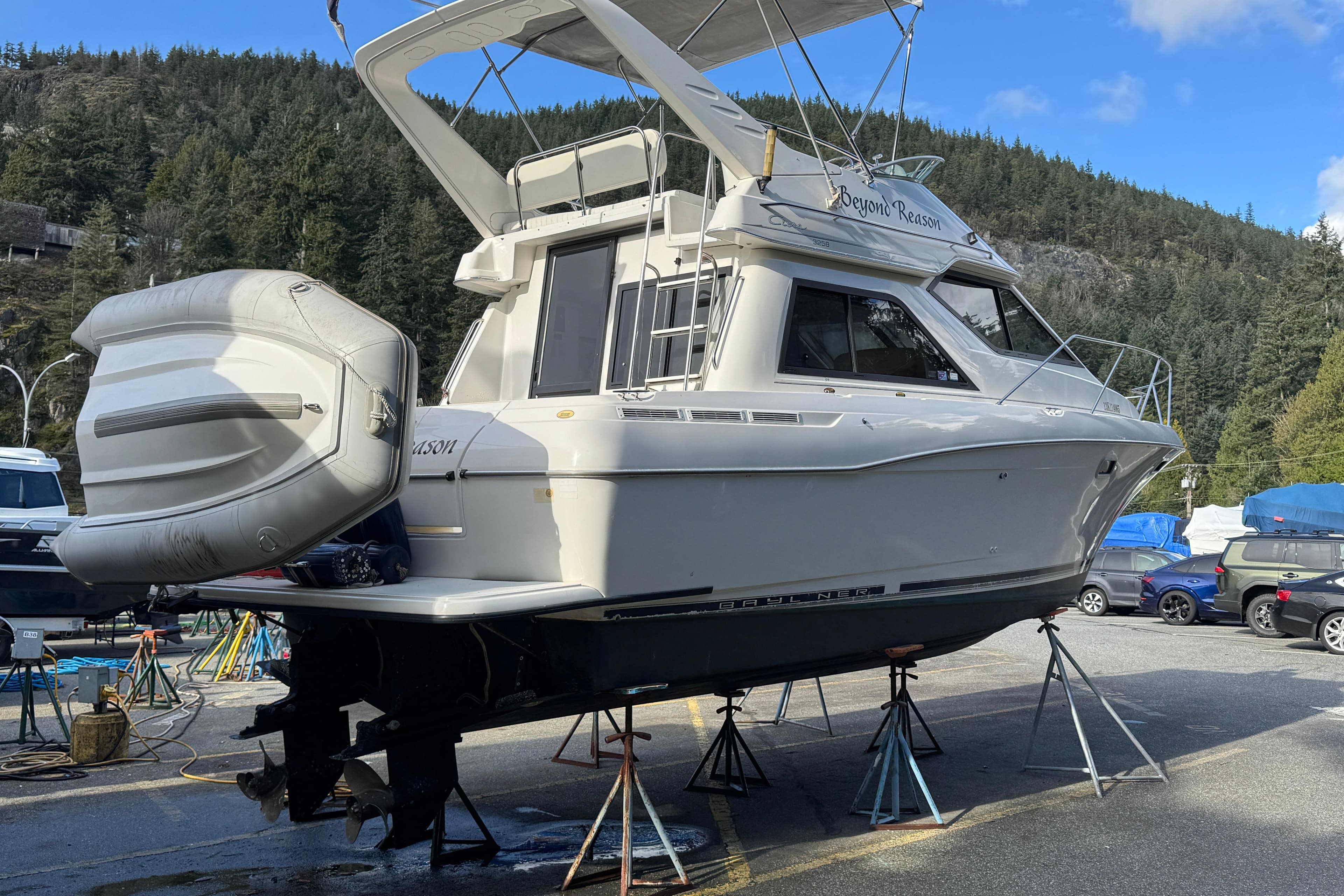 2000 Bayliner 3258 Ciera Command Bridge DX on stands, surrounded by trees and vehicles.