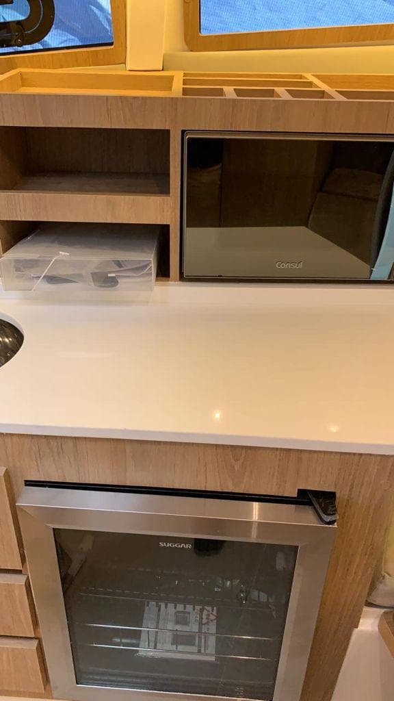 Modern kitchen area in 2021 NX Boats 340 Sport Coupe with microwave and mini fridge.