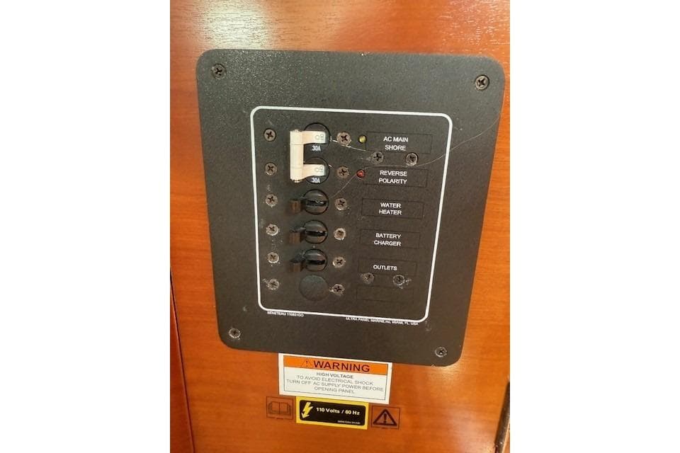 Electrical panel on a 2002 Beneteau First 36.7 sailboat, featuring various switches and warnings.