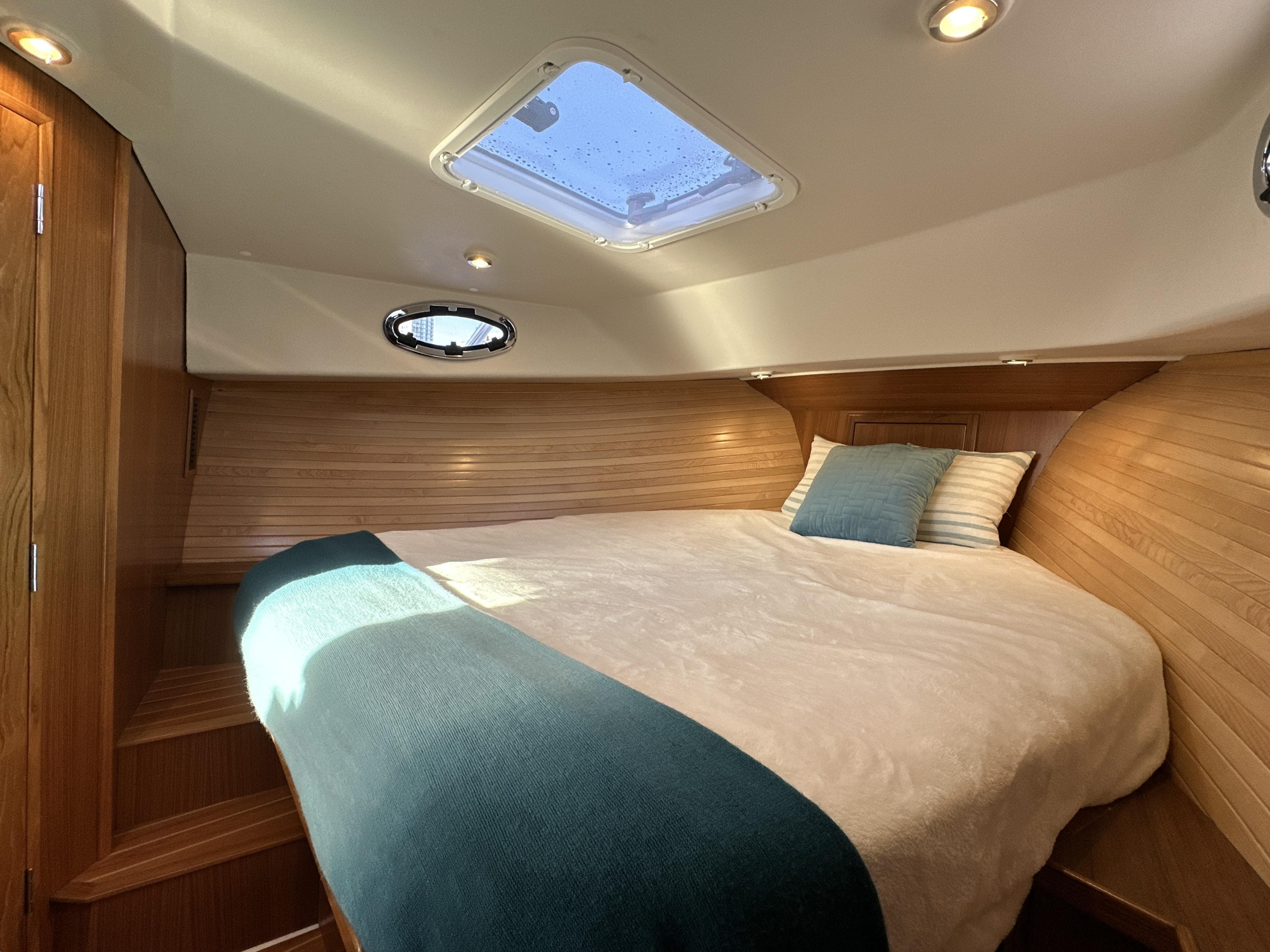 2025 True North 34 Outboard Express cabin with cozy bed and skylight.