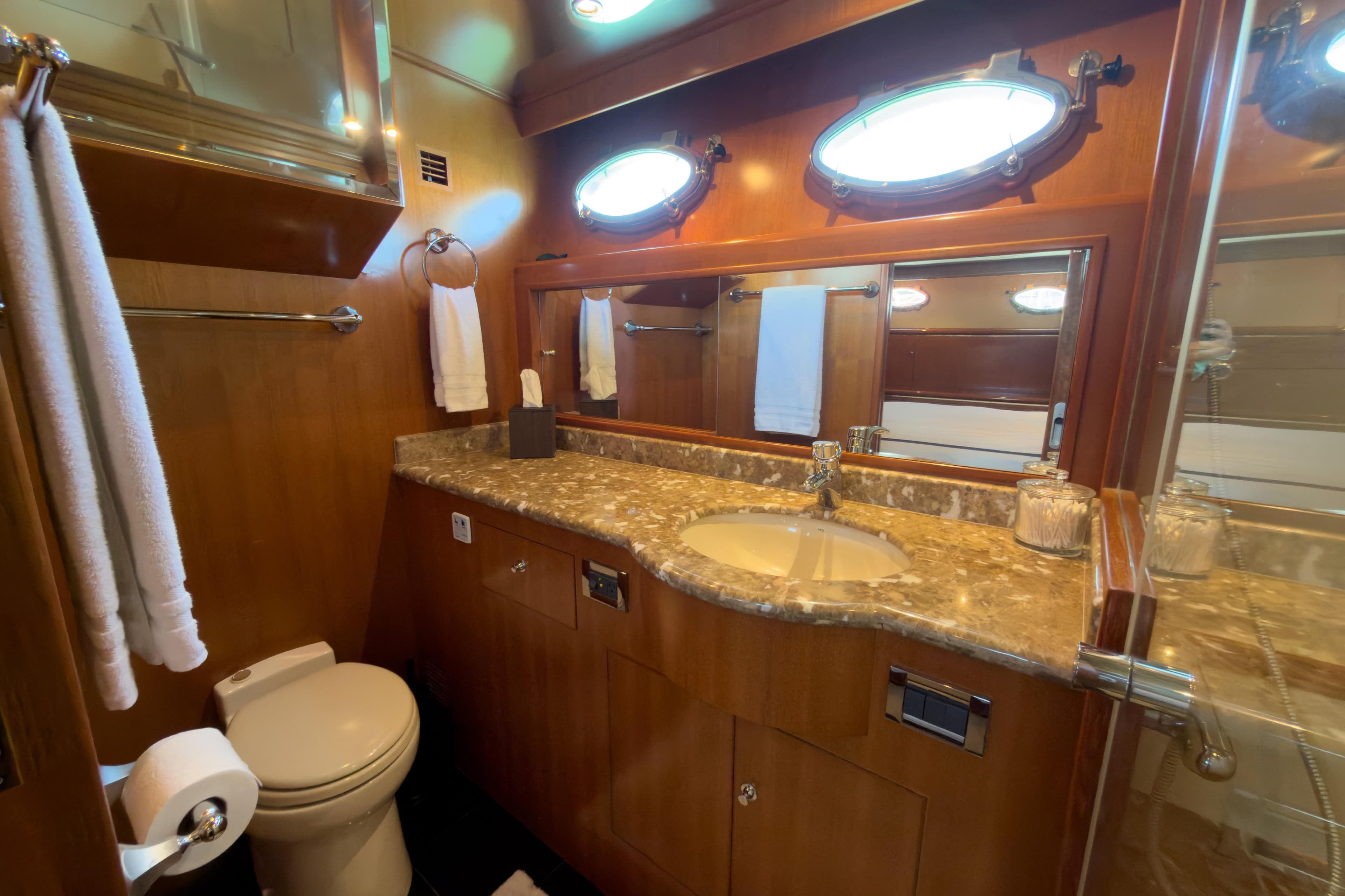 Luxurious bathroom in 2003 Ocean Alexander 700 Classicco yacht with marble countertop and porthole windows.